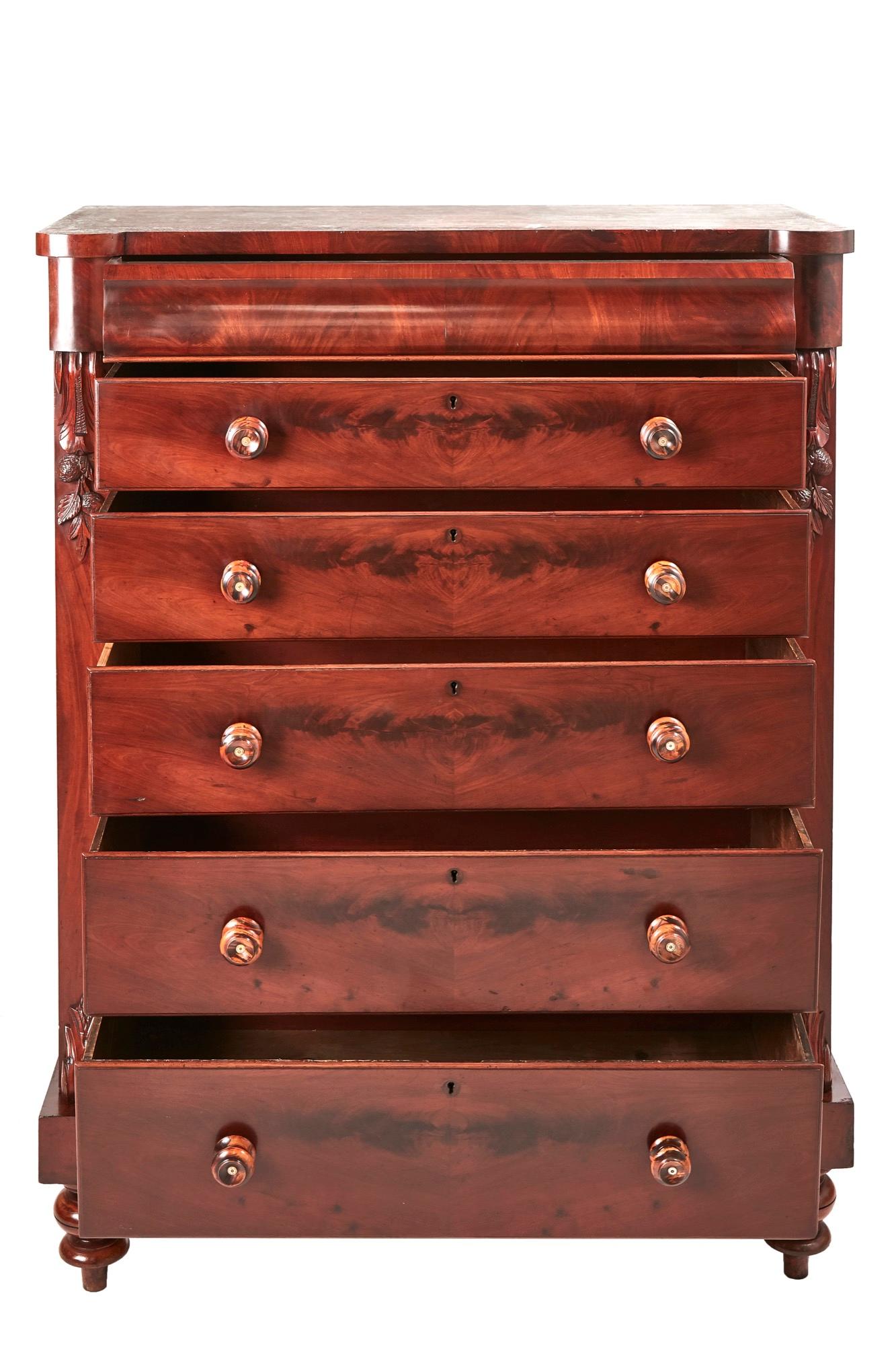 This is a quality antique tall 19th century Victorian antique mahogany chest of drawers having six long mahogany drawers with original turned knobs and attractively carved mahogany supports. It stands on a plinth base with turned feet.

An