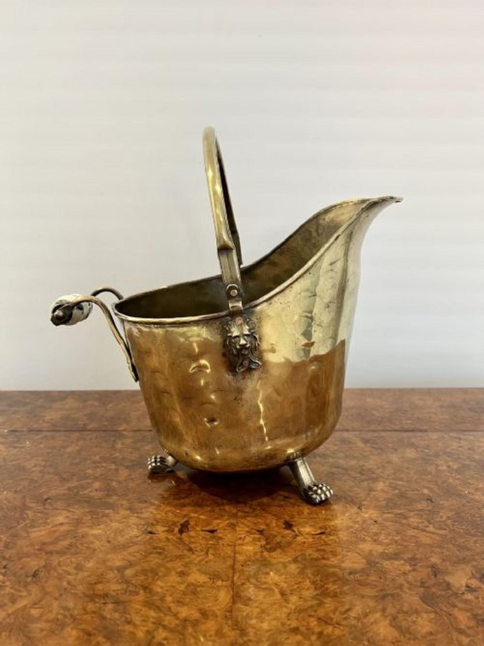 Quality antique Victorian brass coal scuttle having a quality antique Victorian brass coal scuttle with a swing handle to the top and a handle to the back, with lions head to both sides standing on three brass paw feet 