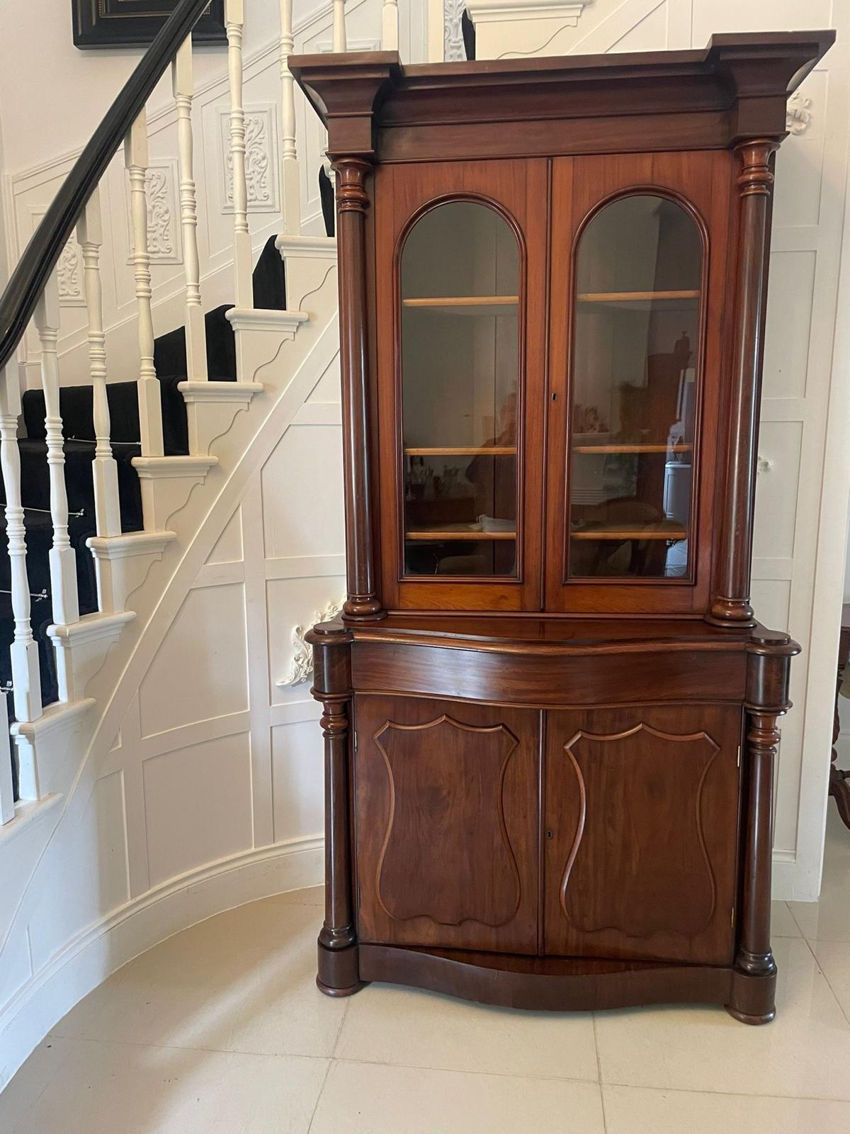 Antica libreria vittoriana di qualità in mogano con un'attraente cornice sagomata sopra una coppia di porte vetrate con modanature sagomate e colonne tornite. Le porte si aprono per rivelare un interno con ripiani regolabili. La base ha un bel piano