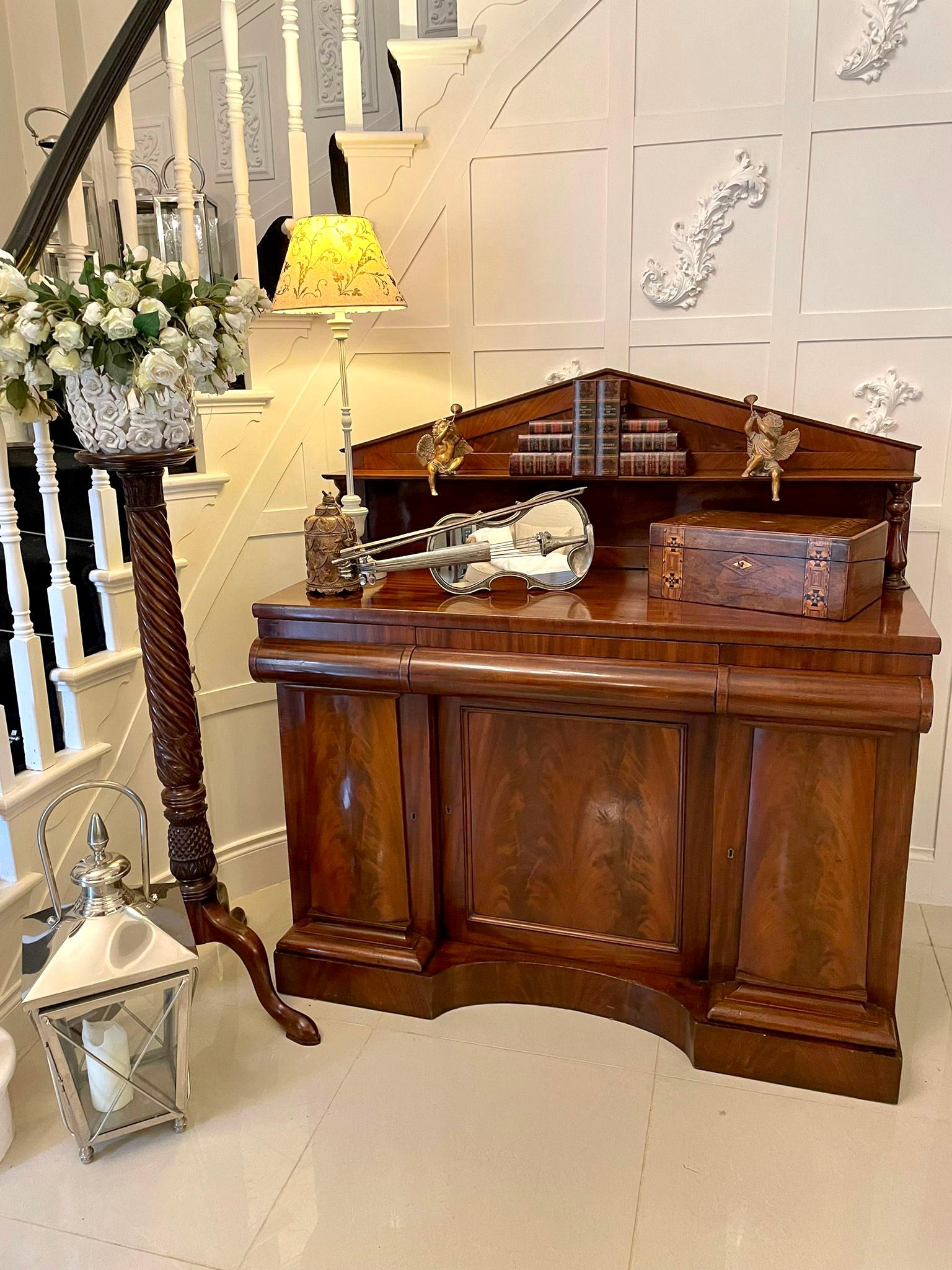 Quality antique William IV figured mahogany sideboard having a mahogany with a shelf and two turned mahogany columns above a quality mahogany top, three shaped frieze drawers above three figured mahogany shaped cupboard doors opening to reveal a