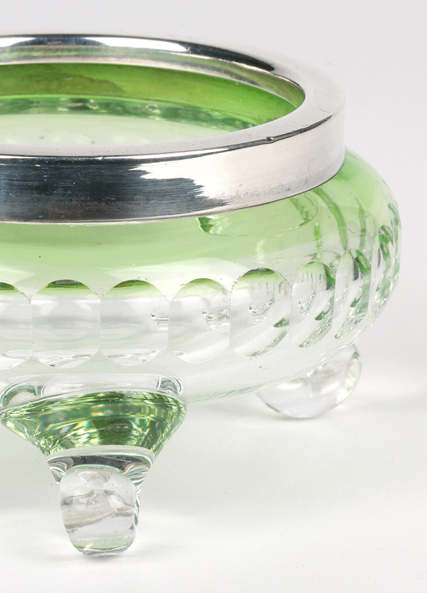 Fino cuenco con pie de vidrio Art Nouveau inglés con borde de plata fechado en 1904. Atribuido a Stourbridge o a Stevens & Williams, el cuenco de cristal tiene forma redonda y achaparrada y se alza sobre tres patas enroscadas. El plato es de vidrio