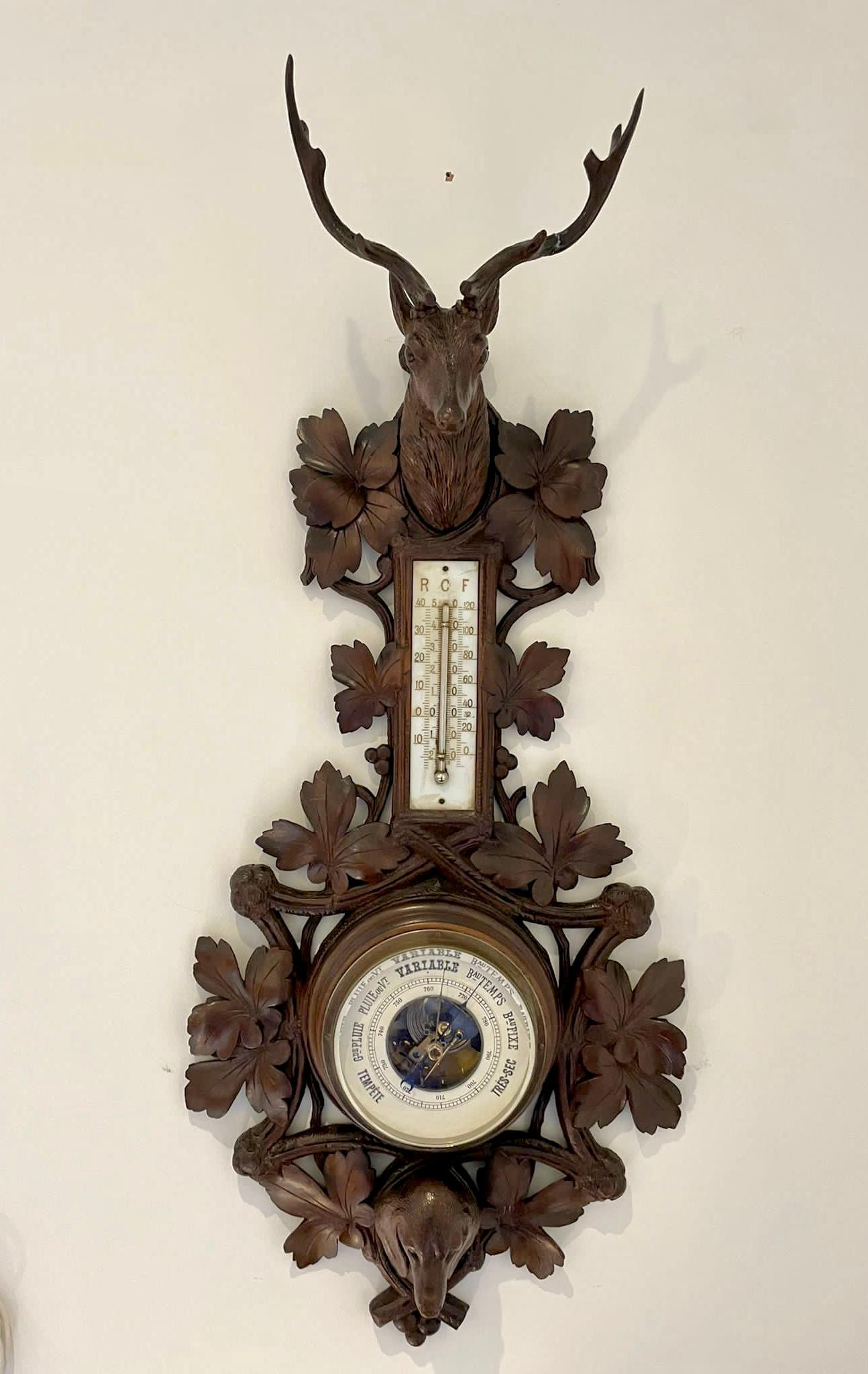 Quality Black Forest carved walnut barometer having a quality carved walnut shaped case with a carved stag's head to the top, carved leaves and foliage and a quality carved walnut dachshund to the base, thermometer and a circular porcelain dial with