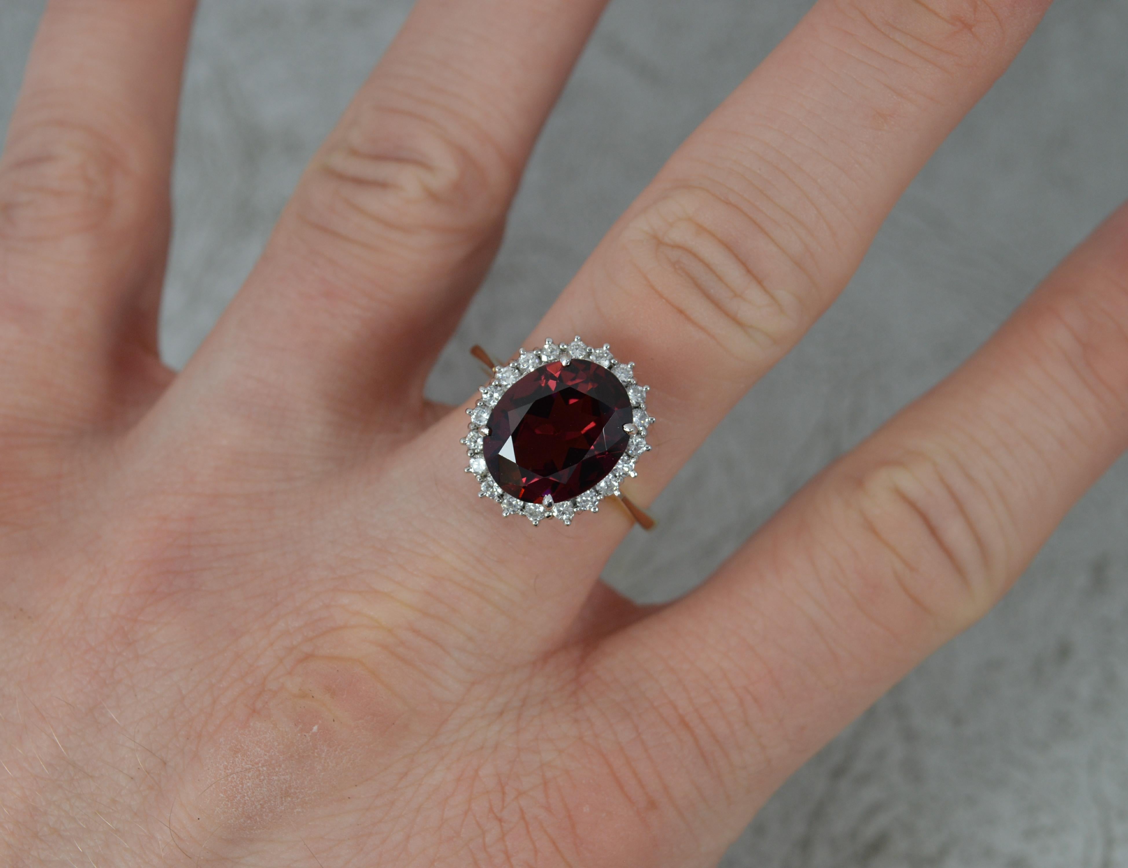 Ein hervorragender zeitgenössischer Cluster-Verlobungsring.
Massiver 18-Karat-Gelbgold-Schaft mit Weißgold-Kopfkrallenfassung.
Mit einem großen Granat im Ovalschliff in der Mitte in einer Fassung mit vier Krallen. 10mm x 12mm ca. Umgeben ist eine