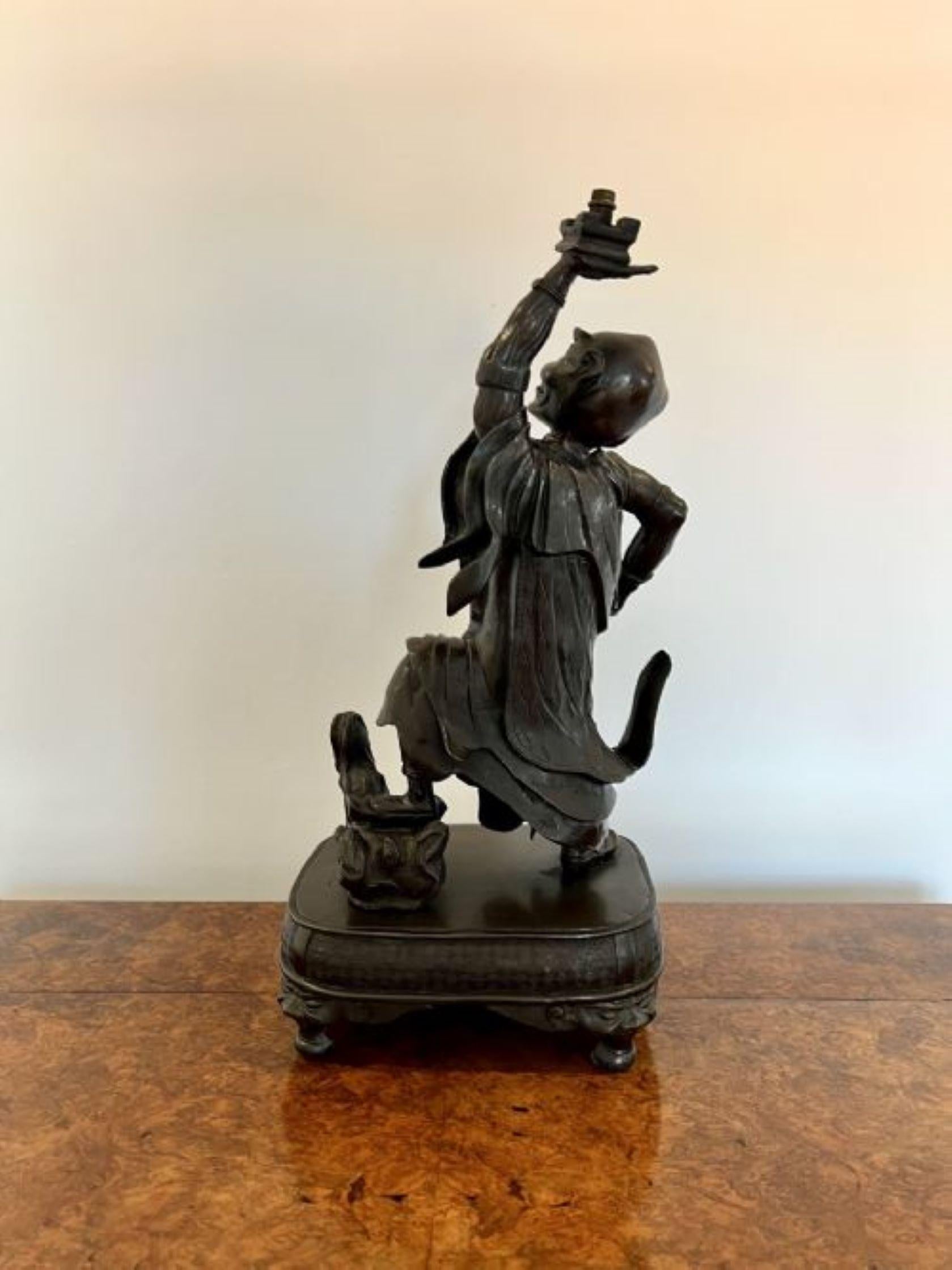 Quality large antique Japanese bronze figure having a quality large antique Japanese bronze figure of a man holding his left arm aloft standing with one foot on a rock raised on a rectangle ornate base raised on bun feet. 