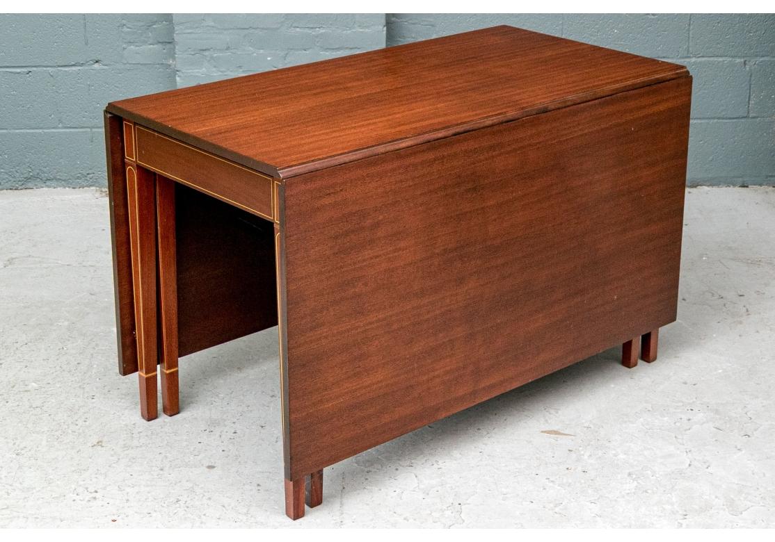 CA. 1950's. With the Maryland company label and genuine mahogany label. An elegant classical style mahogany dining table with deep leaves. The frieze and square tapering legs are string inlaid enhanced. With a single frieze drawer. There are two