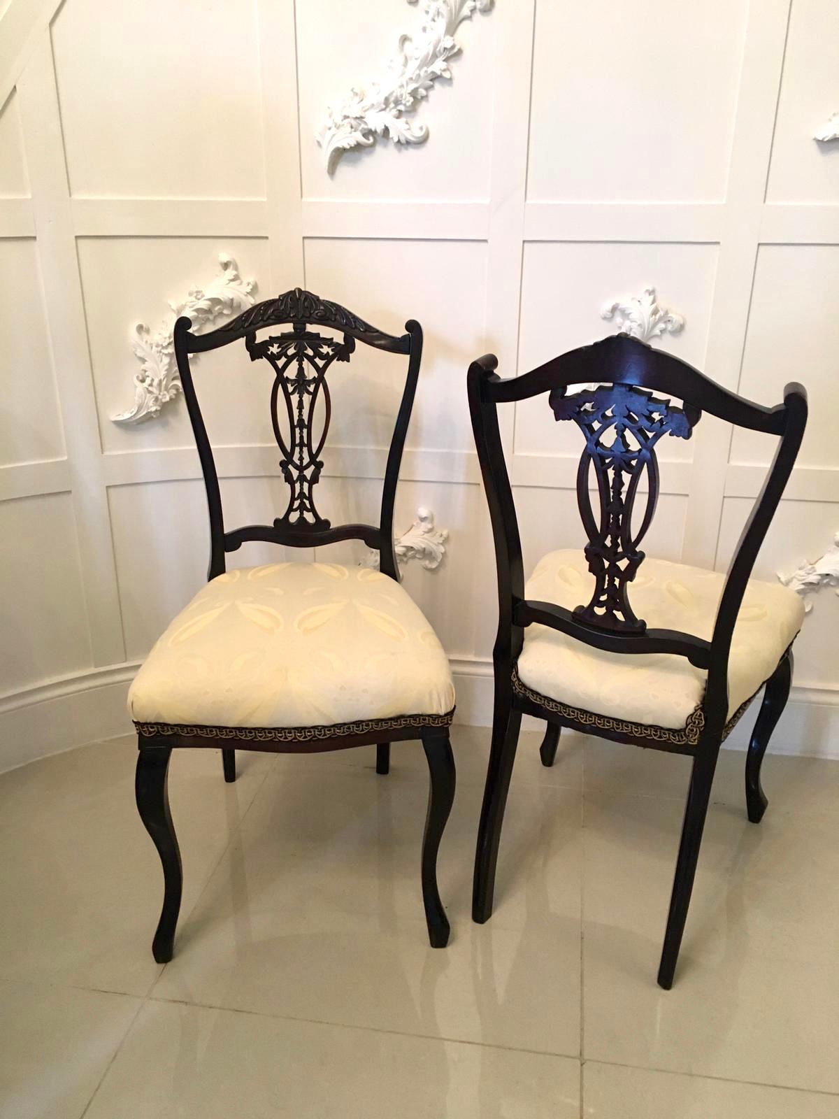 A quality pair of antique carved rosewood desk or side chairs. This pair have a very attractively carved top rail and center splat. They have been tastefully reupholstered in a quality fabric. They are raised on cabriole legs to the front and out