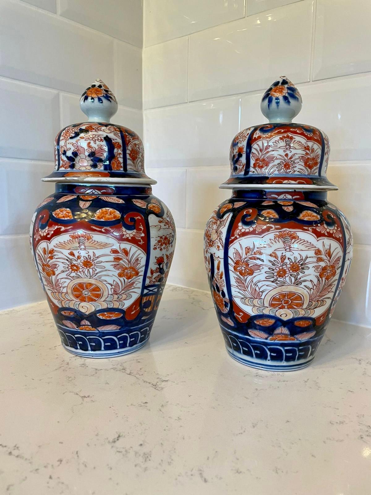 Quality pair of antique Imari lidded vases having wonderful hand painted panels with flowers, leaves, birds and trees in fantastic red, blue, green and gold colours. 

Beautifully decorative; small chips to one lid which does not distract from how