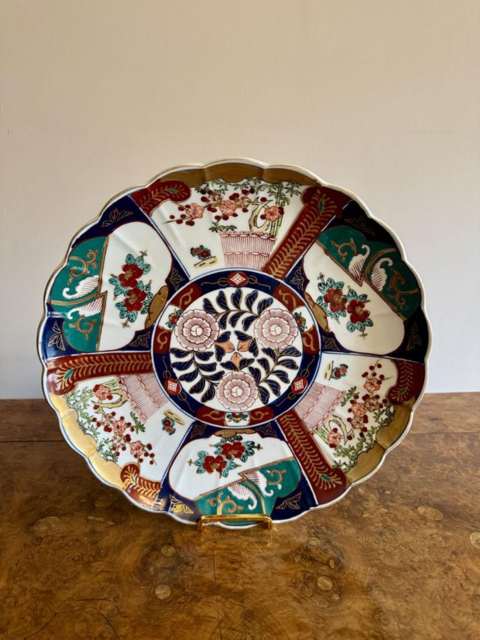 Pareja de cargadores imari japoneses antiguos de calidad, con borde ondulado decorado con flores, árboles y volutas en vibrantes colores rojo, azul, verde, blanco y dorado. 

D. 1920