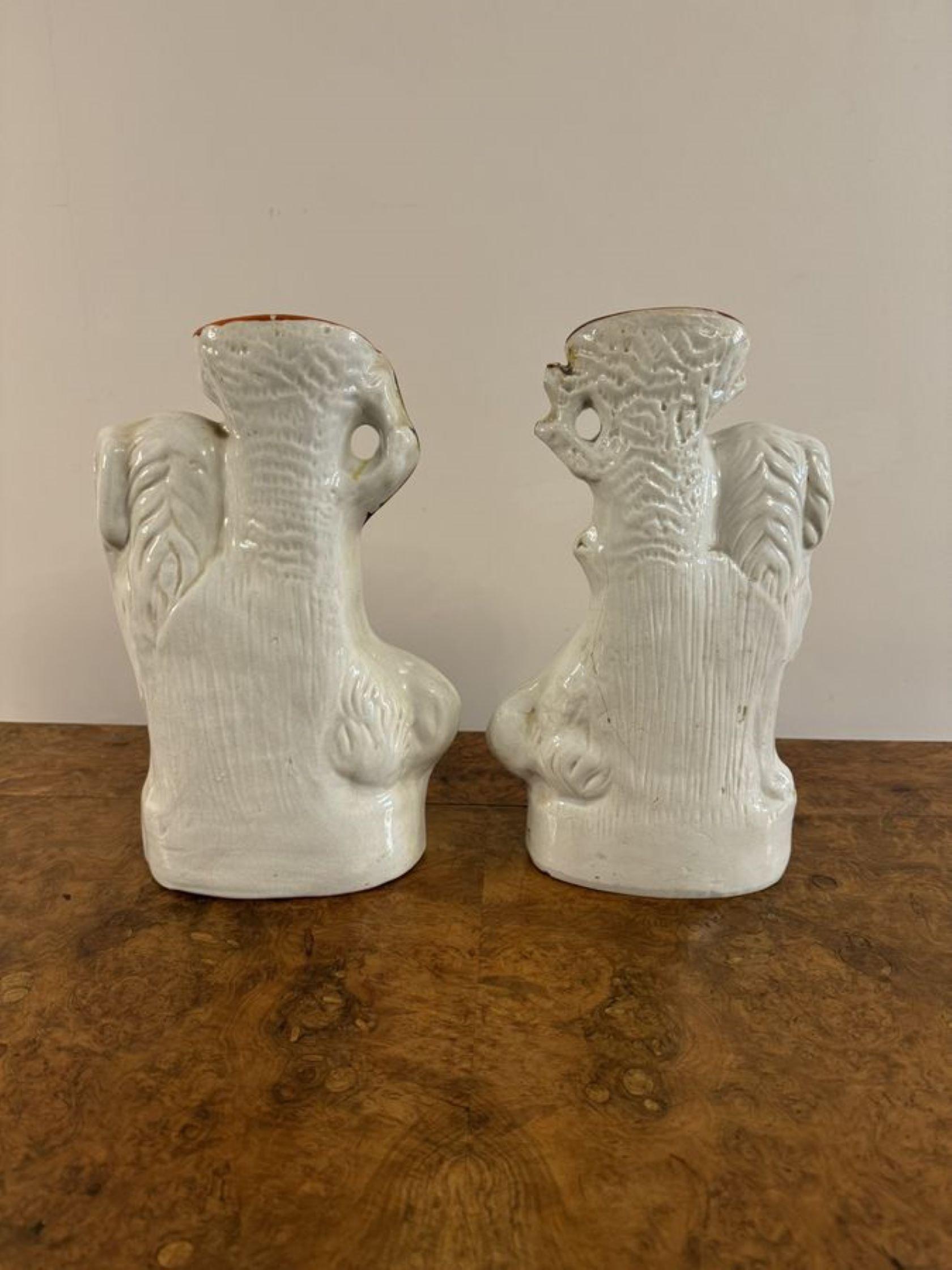 Quality pair of antique Victorian Staffordshire spaniel spill vases, having a matching pair of spaniels with white coats and gold flecks, matching white and gold collars and padlocks, mounted on oval shaped bases surrounded by foliage, with a shaped