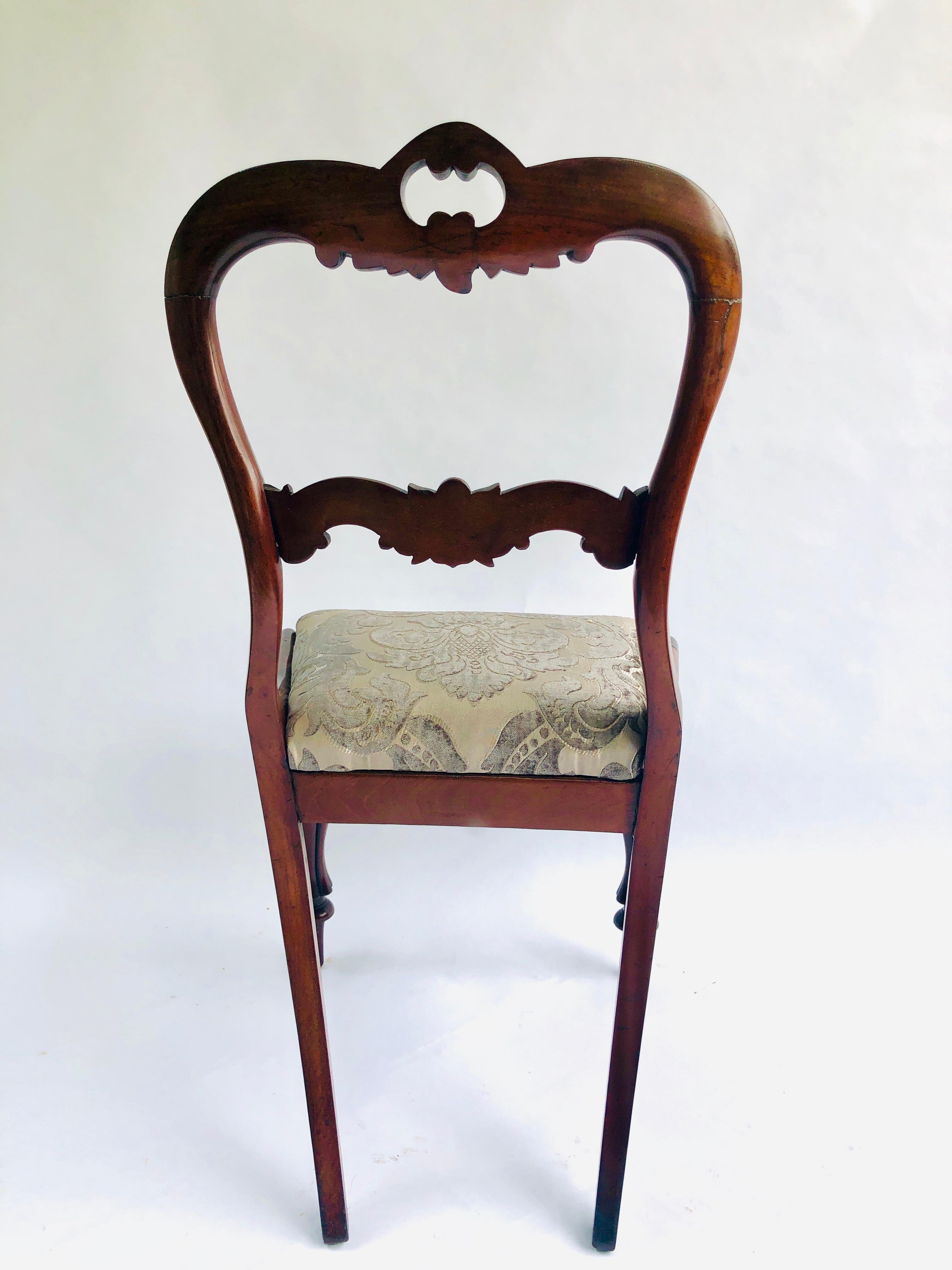 A quality pair of antique William IV carved hardwood side/desk chairs. This pair has a very attractively carved top rail and centre splat. They have been tastefully reupholstered in a quality fabric. They are raised on cabriole legs to the front and