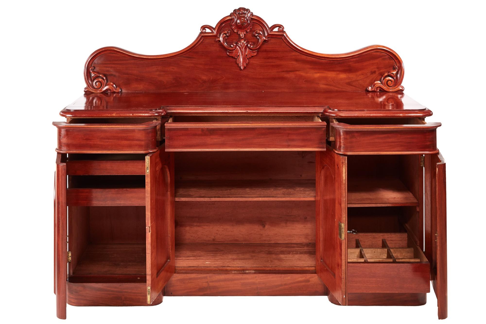 A fine quality antique 19th century Victorian antique carved mahogany sideboard with a delightful shaped carved back, excellent quality mahogany top, three frieze drawers, four quality figured mahogany paneled door. The fitted interior is of the