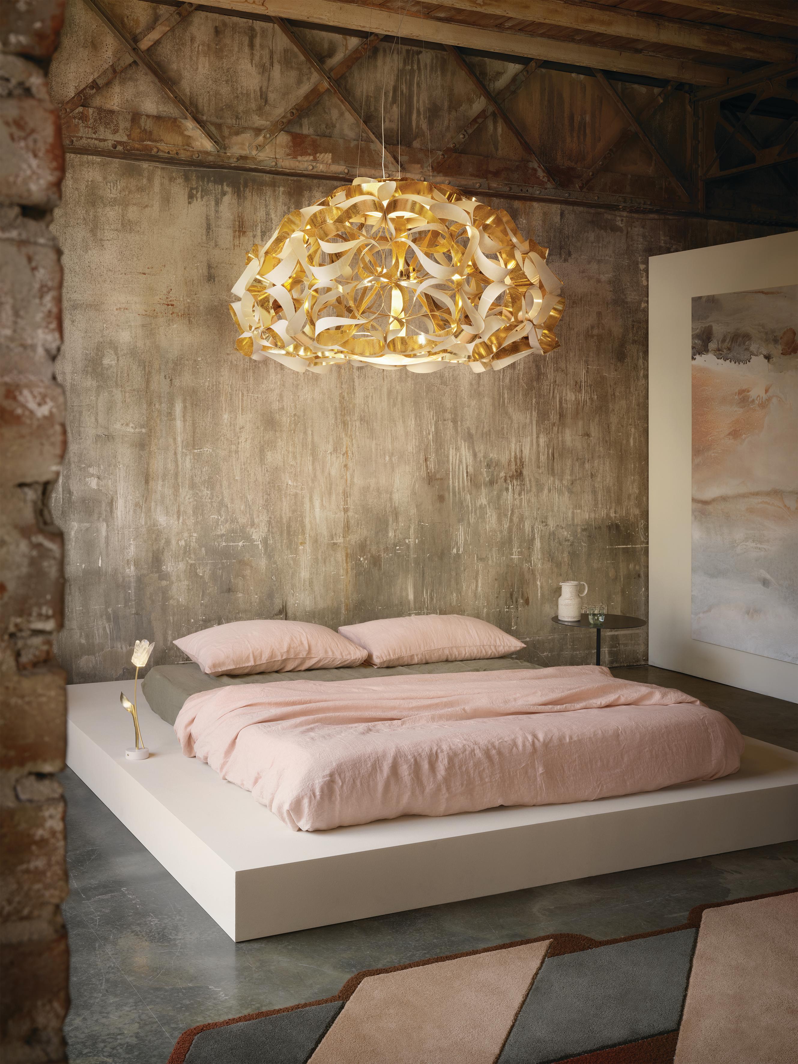Quantica is inspired by the “quantum entanglement” concept, representing the cosmic entwinement of elements. Light interacts with shape in a luxurious, dense sculpture perfect for both private and commercial spaces. The golden textile effect has