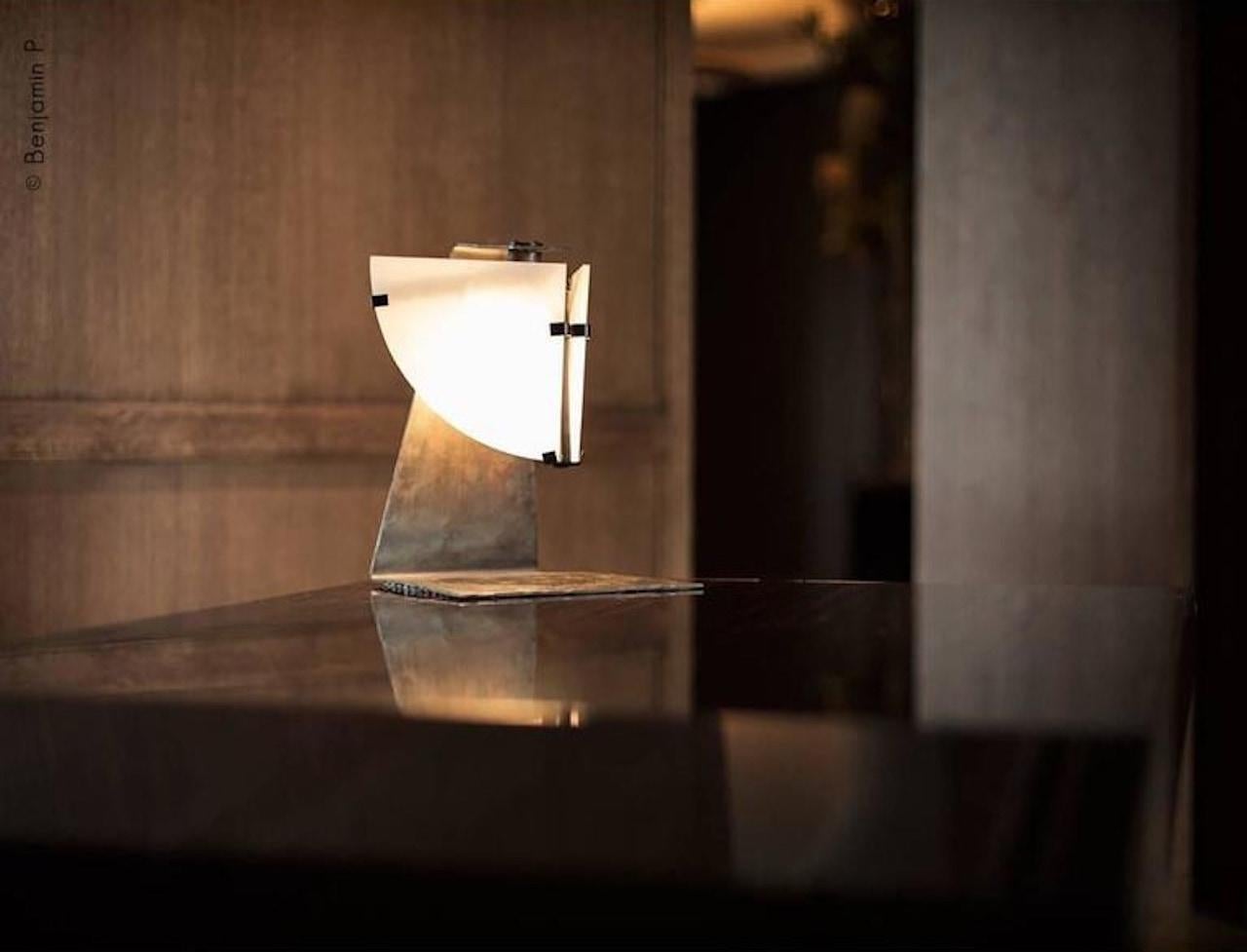 Designed in 1922, this pivoting lamp is symbolic of Pierre Chareau's cubist inspiration. Like a statue, it stares out from the two alabaster panels forming the face, the metal forming the body.