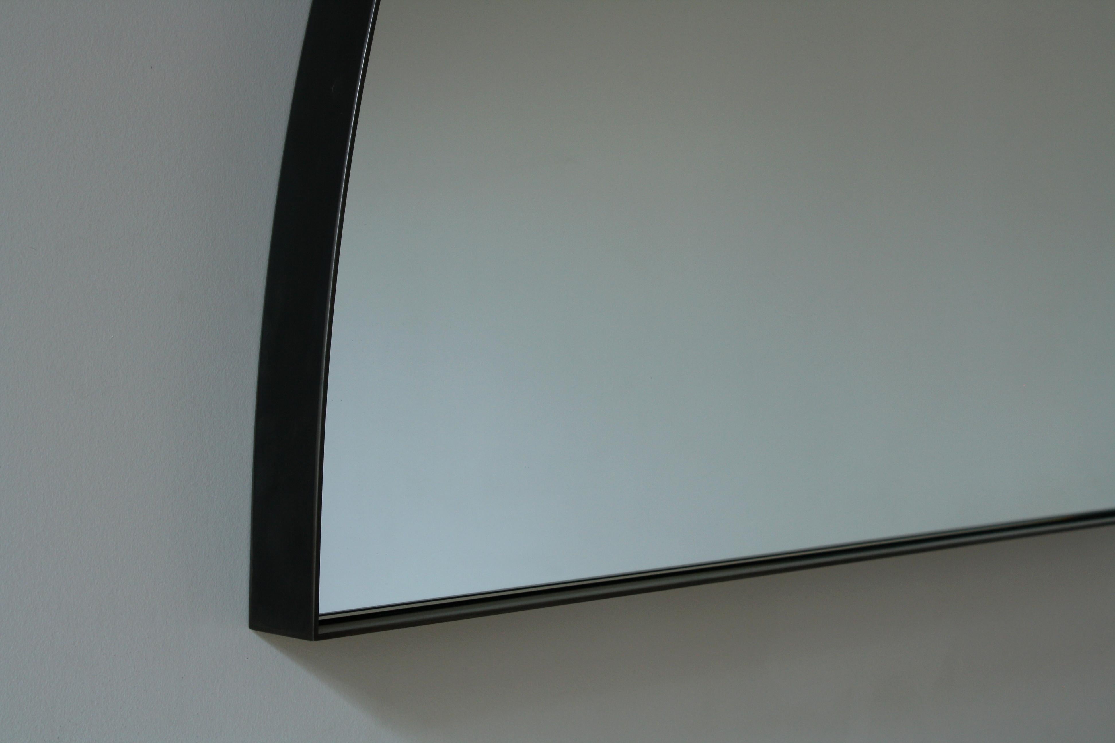 Shown with a quarter round blackened steel frame and clear glass mirror (the listing is for a blackened steel frame - also shown with brass frame)
Measures: 42” wide x 42” high x 2” deep

A sweeping metal arc creates an atypical mirror shape - that