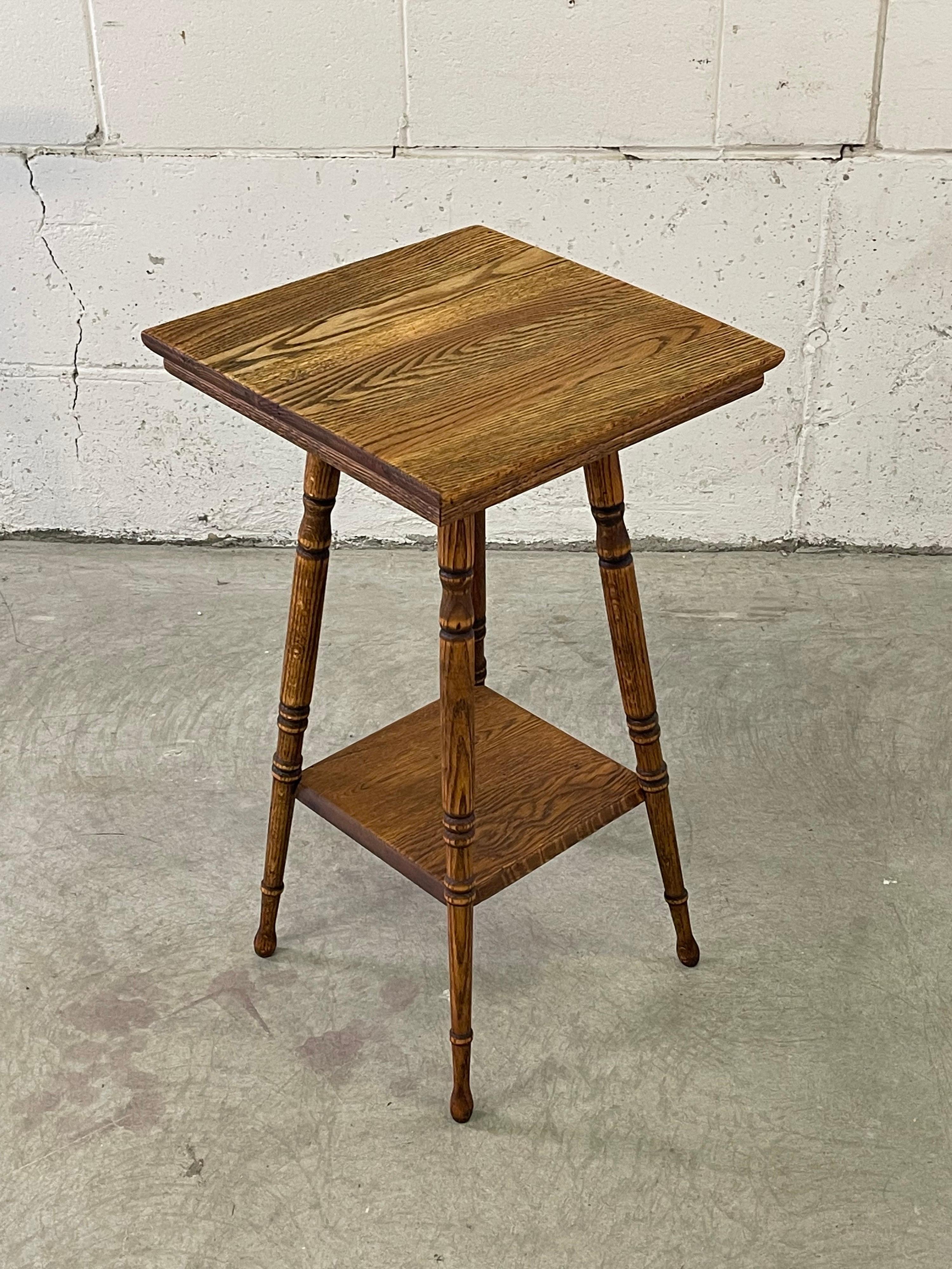 Vintage quarter-sawn oak square top side table or plant stand. Additional shelf for storage. Legs have a nice turned design. No marks.