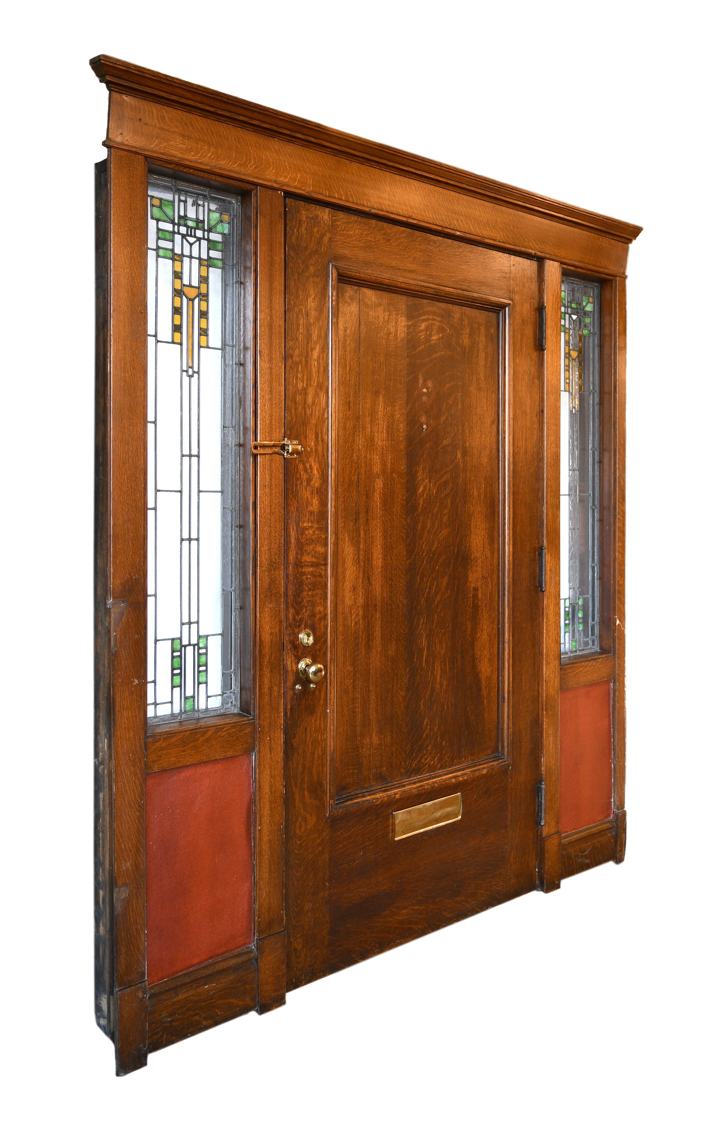 Quartersawn exterior door unit with oversized solid door and Arts & Crafts sidelite windows complete with all original hardware and inside trim. The two stained glass windows on each side of the door give this outstanding piece even more character!