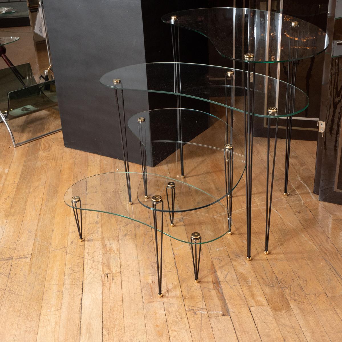 Quartet of glass kidney shaped graduated size tables with black metal legs.
Measurements for individual tables:
Small - 23.5