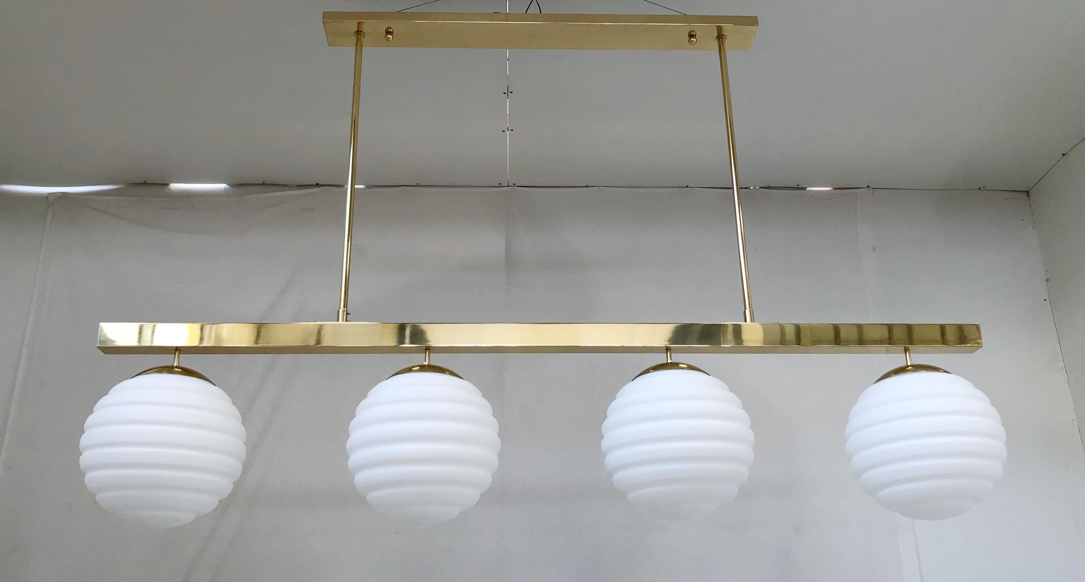Italian pendant chandelier shown in white ribbed Murano glass globes, mounted on polished brass frame / Designed by Fabio Bergomi for Fabio Ltd / Made in Italy
4 lights / E26 or E27 type / max 40W each
Measures: width 70 inches, depth 12 inches,