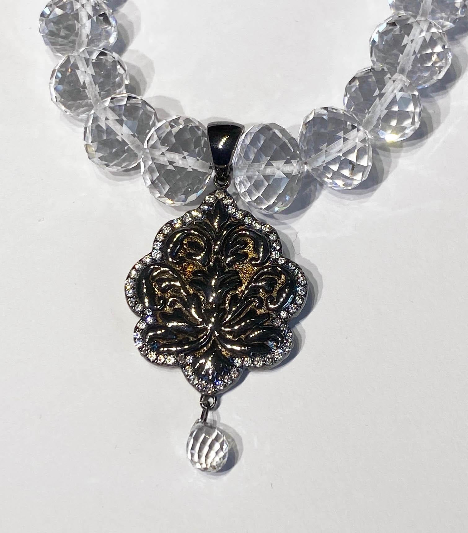 A White Quartz Rondelle Beaded Necklace with a Blackened Silver Pendant set with White Sapphires. The White Quartz Beads graduate in size from 7.5MM to 12MM. The Pendant contains 8.6 Grams of Blackened Silver and is set with 2.4 Carats of White