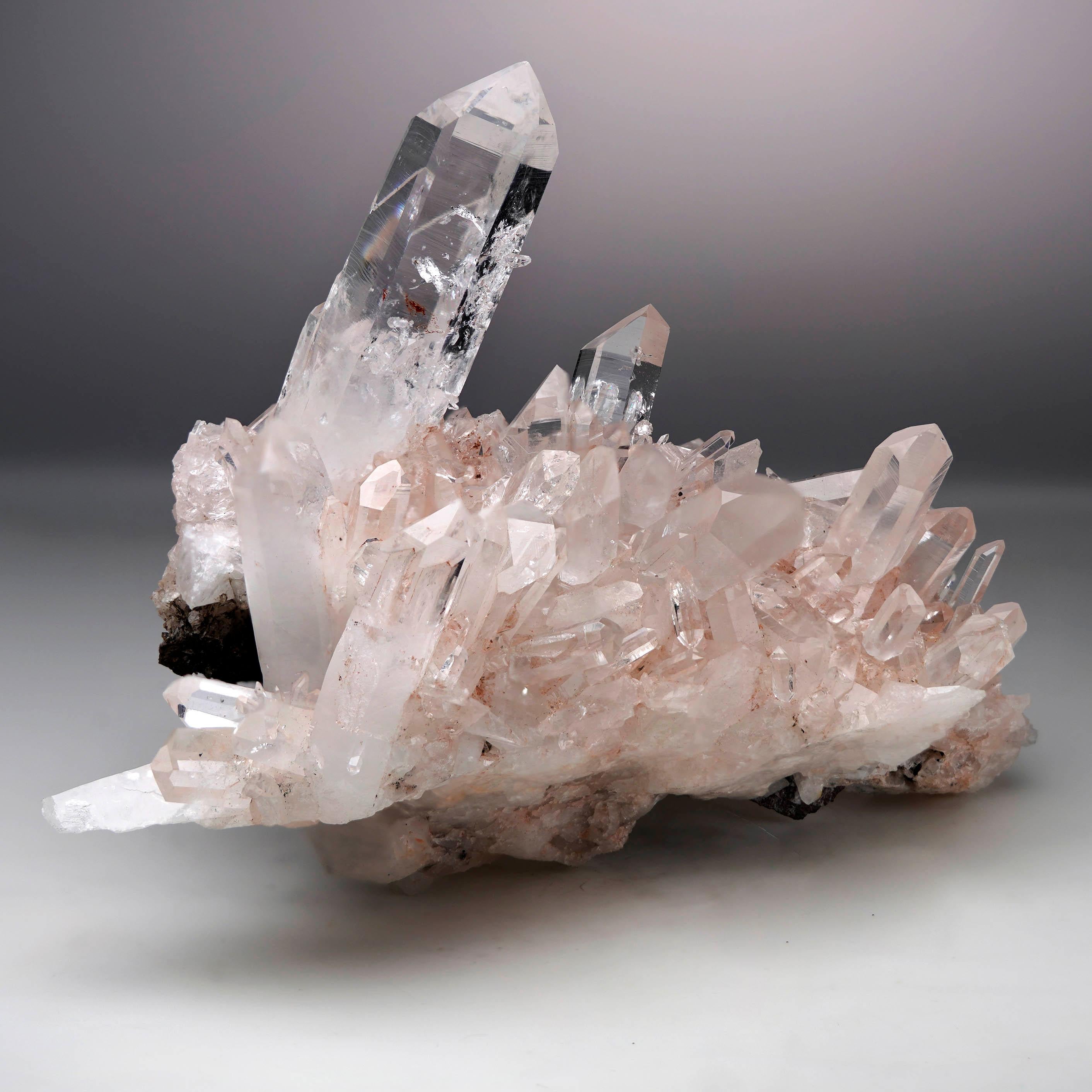This stunning natural Rose Quartz cluster showcases crystal-clear Quartz formations with mesmerizing pink inclusions of Lithium tinting the matrix and lower part of the Quartz crystals forming the cluster. The delicate contrast between the