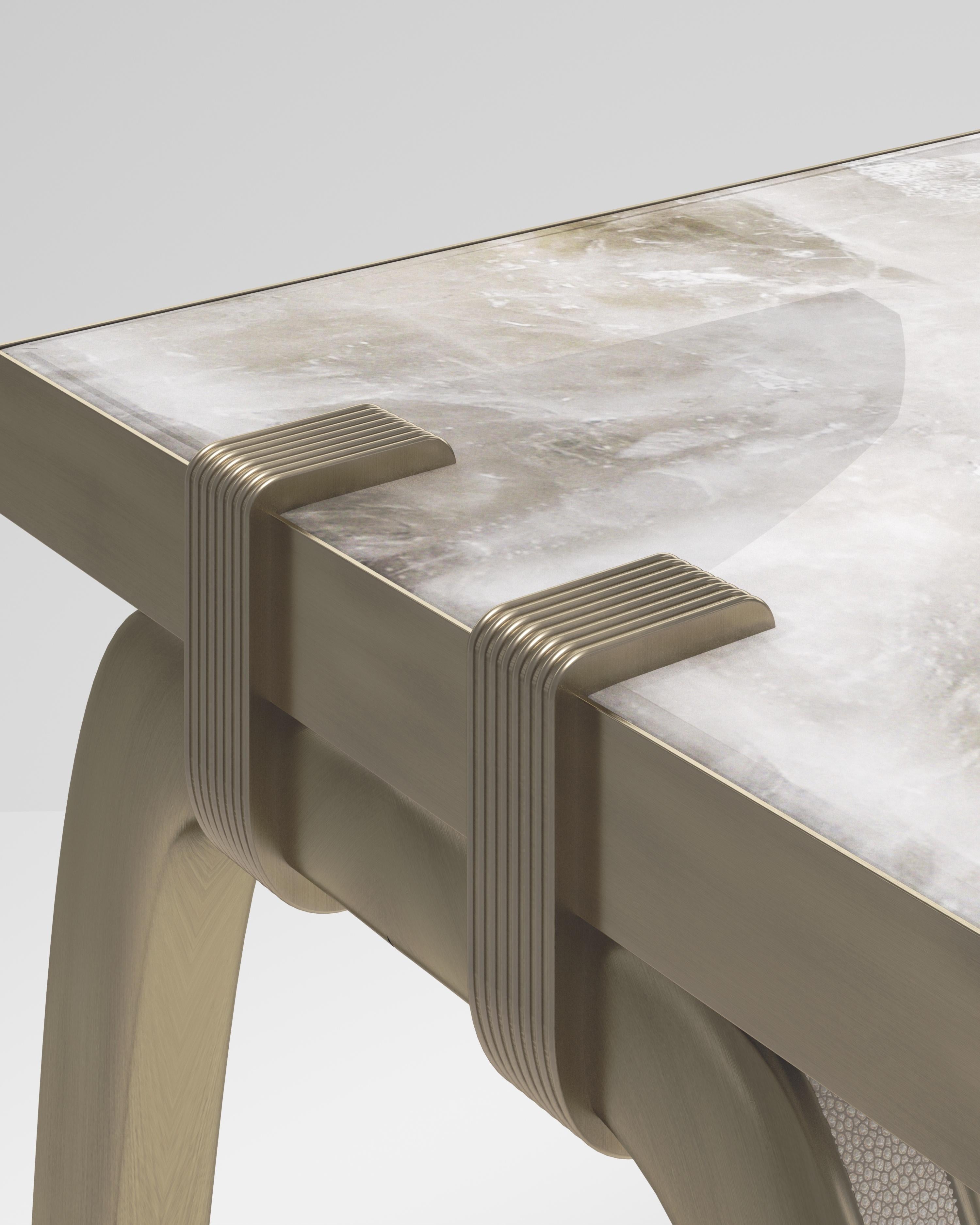La table console Sonia est un modèle emblématique d'Augousti, qui met en valeur le savoir-faire artisanal de la marque. Les pieds incrustés de galuchat se fixent sur le côté du plateau rectangulaire en quartz. Cette pièce est un clin d'œil à la