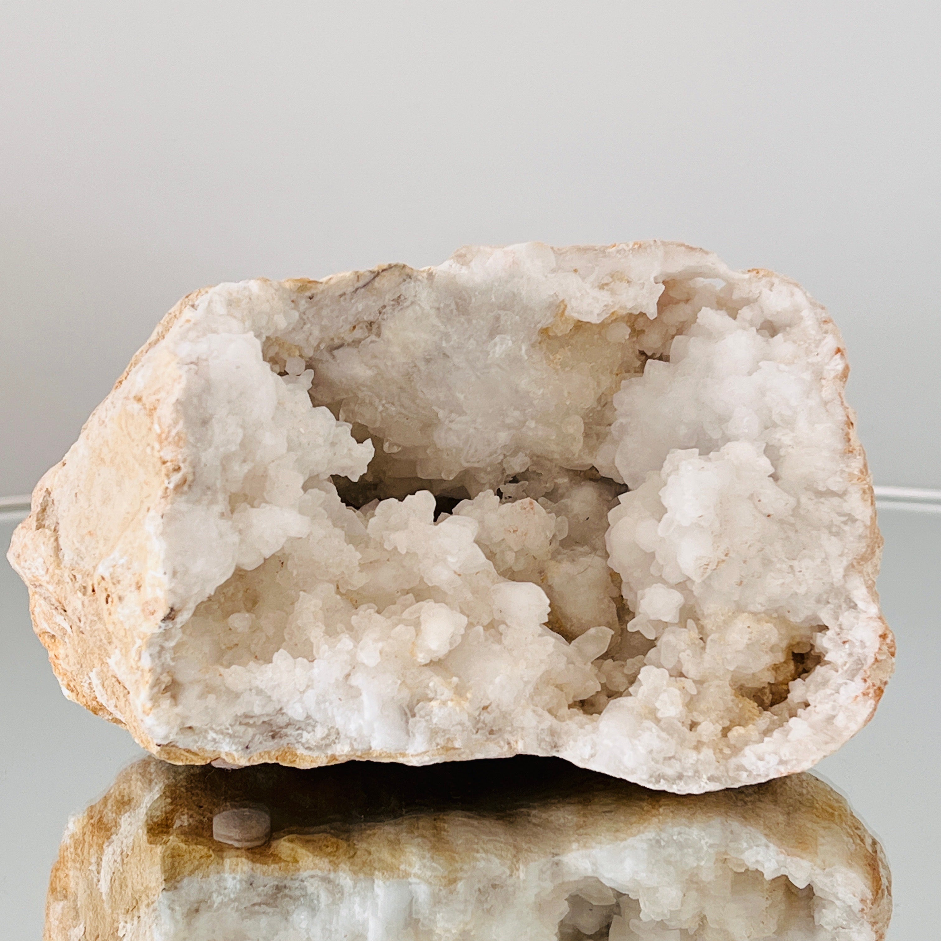 Natürlicher Quarzkristall mit einem weißen kristallinen Zentrum, umgeben von einem Felsen in hellbraunen oder beigen Farbtönen.  Mit einer Entstehungszeit von bis zu einer Million Jahren ist jede Geode ein Unikat, das jeden Raum um ein organisches,