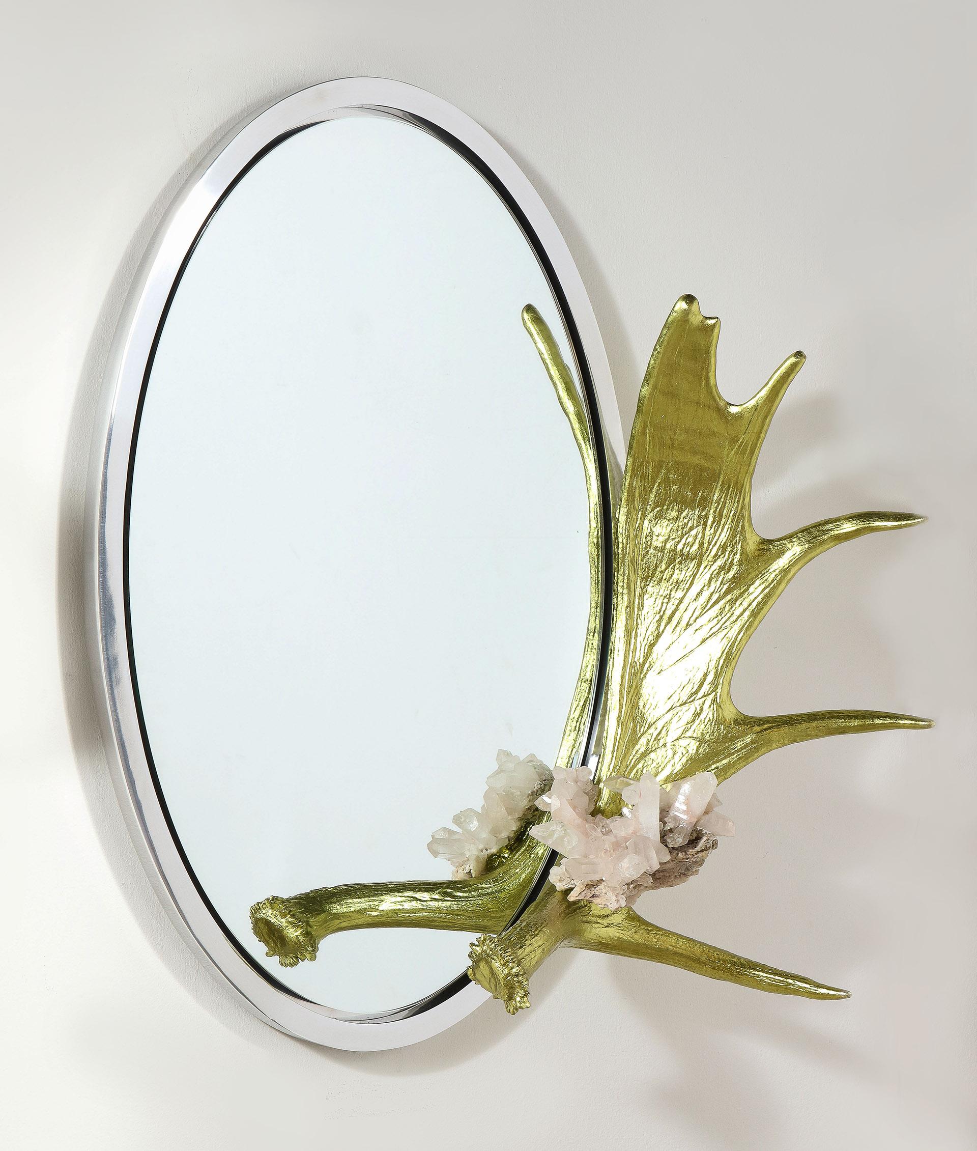 A quartz crystal mounted onto a silver leaf Alaskan Moose Paddle, the whole mounted to an oval mirror with a polished stainless steel frame.