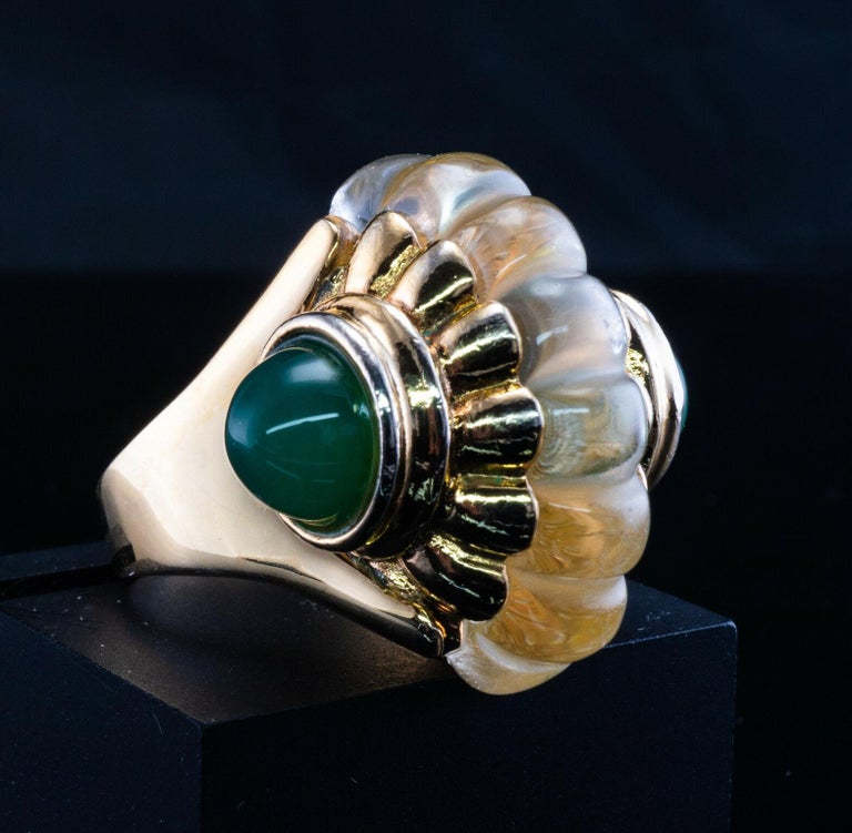 This very unique vintage ring is finely crafted in solid 14K gold and set with rock crystal and green chalcedony cabochons. The carved fluted crystal in the center is white and transparent with minor signs of wear. Each green sugarloaf chalcedony