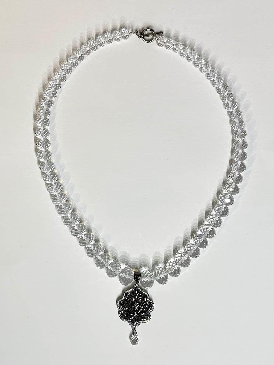 A White Quartz Rondelle Beaded Necklace with a Blackened Silver Pendant set with White Sapphires. The White Quartz Beads graduate in size from 7.5MM to 12MM. The Pendant contains 8.6 Grams of Blackened Silver and is set with 2.4 Carats of White