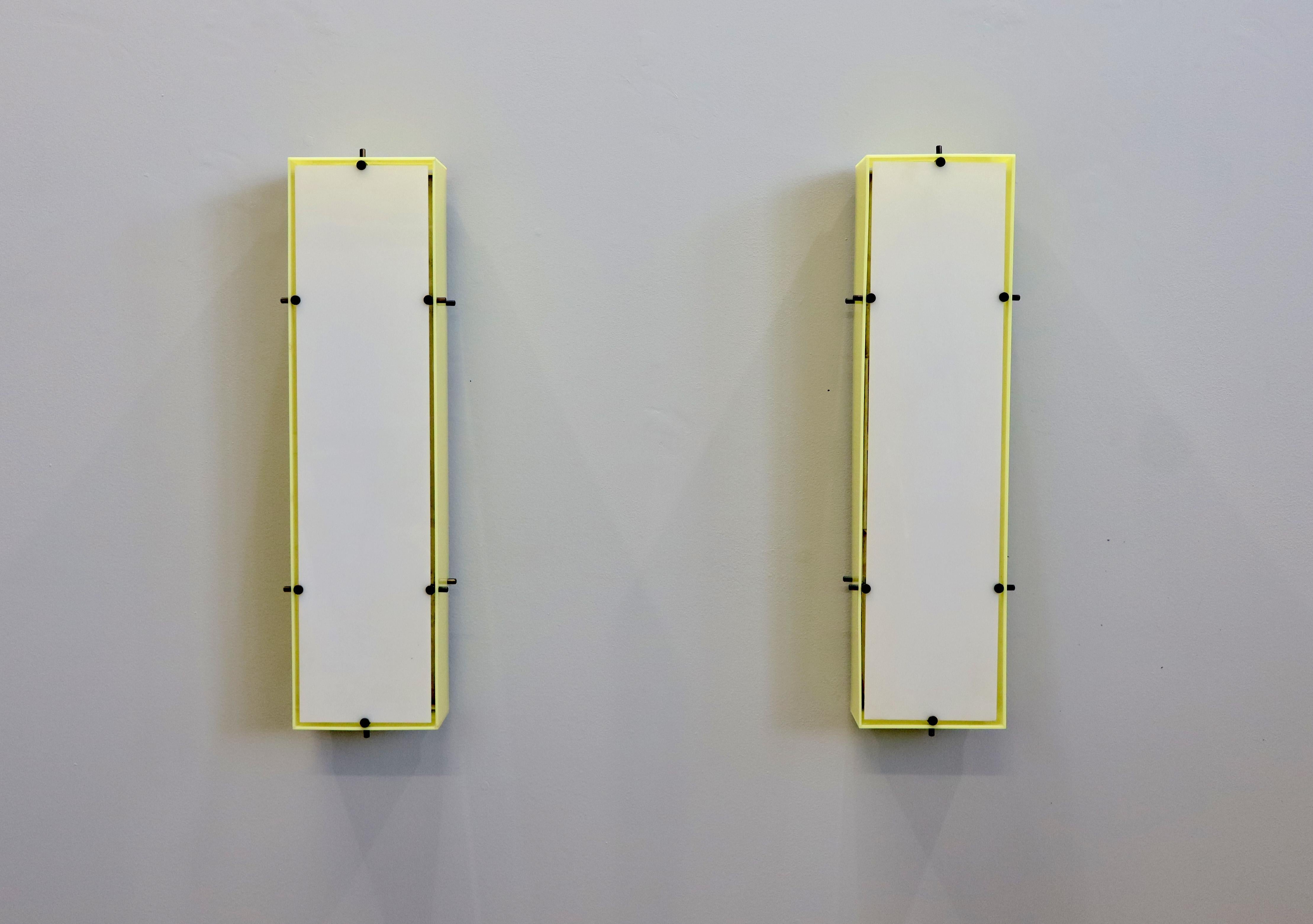 Four wall sconces/lamps designed by Angelo Lelii for Arredoluce, Italy, 1950s. Metal backplate with yellow plexiglass sides and white plexiglass front. Original makers labels present.