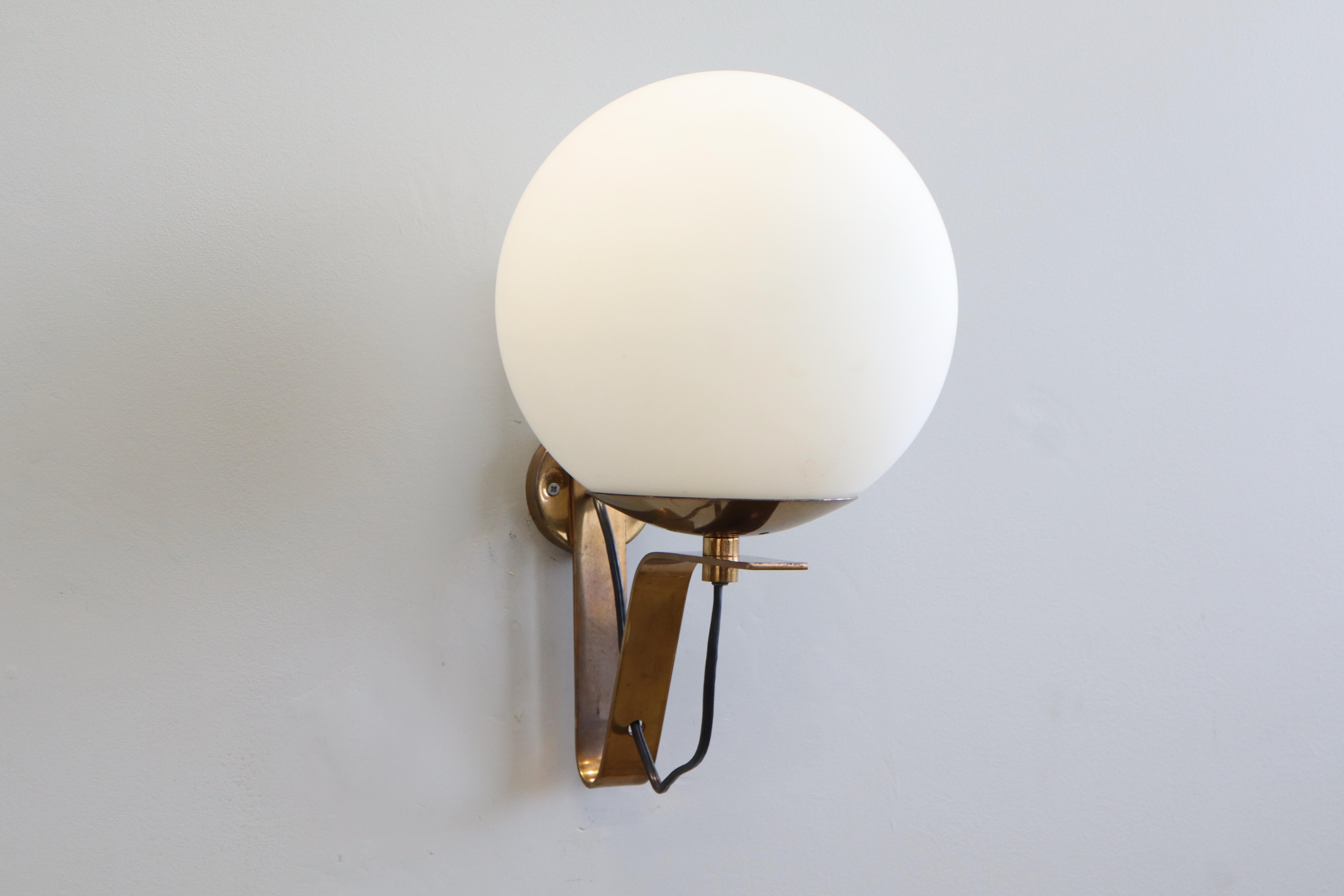 Applique modello b464 di Sergio Asti per Candle. 
Progettato e prodotto in Italia nel 1960 circa. 
Le applique sono montate su una staffa a forma di L in ottone lucido che sostiene senza problemi un globo bianco smerigliato sopra la lampadina