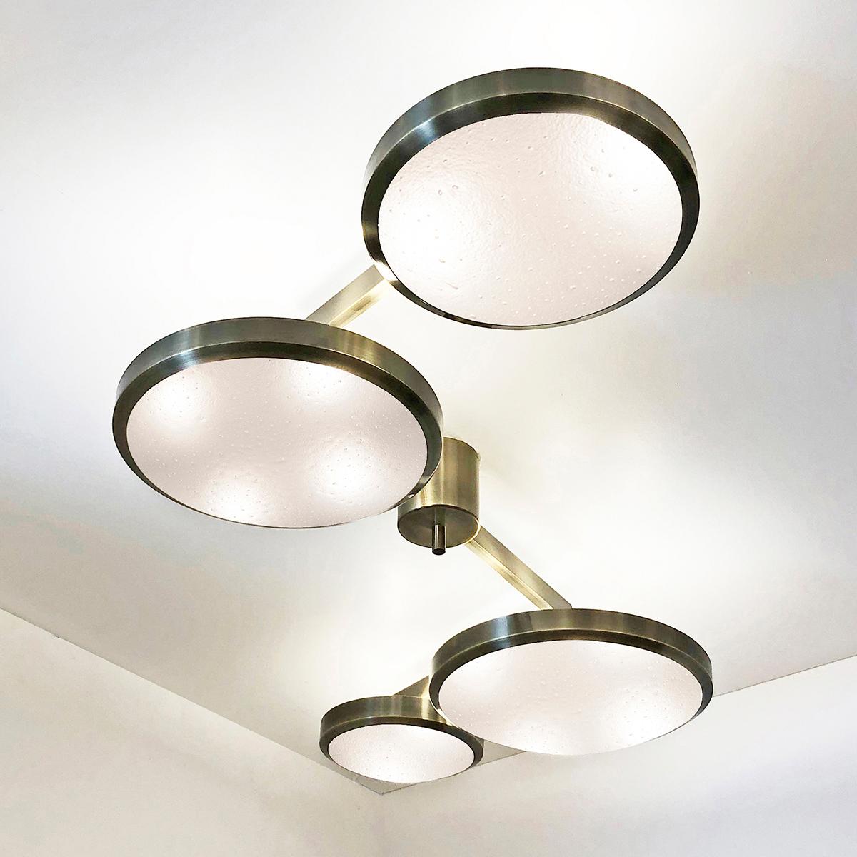 The Quattro ceiling light plays with the notion of lines and shapes, bringing the concept to life with its distinctive winding frame with four variable size shades at staggered heights. The first images show the fixture in our bronzo ottone (bronze)