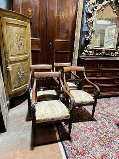 Four carved walnut armchairs with arms, Italy