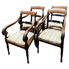 Four carved walnut armchairs with arms, Italy