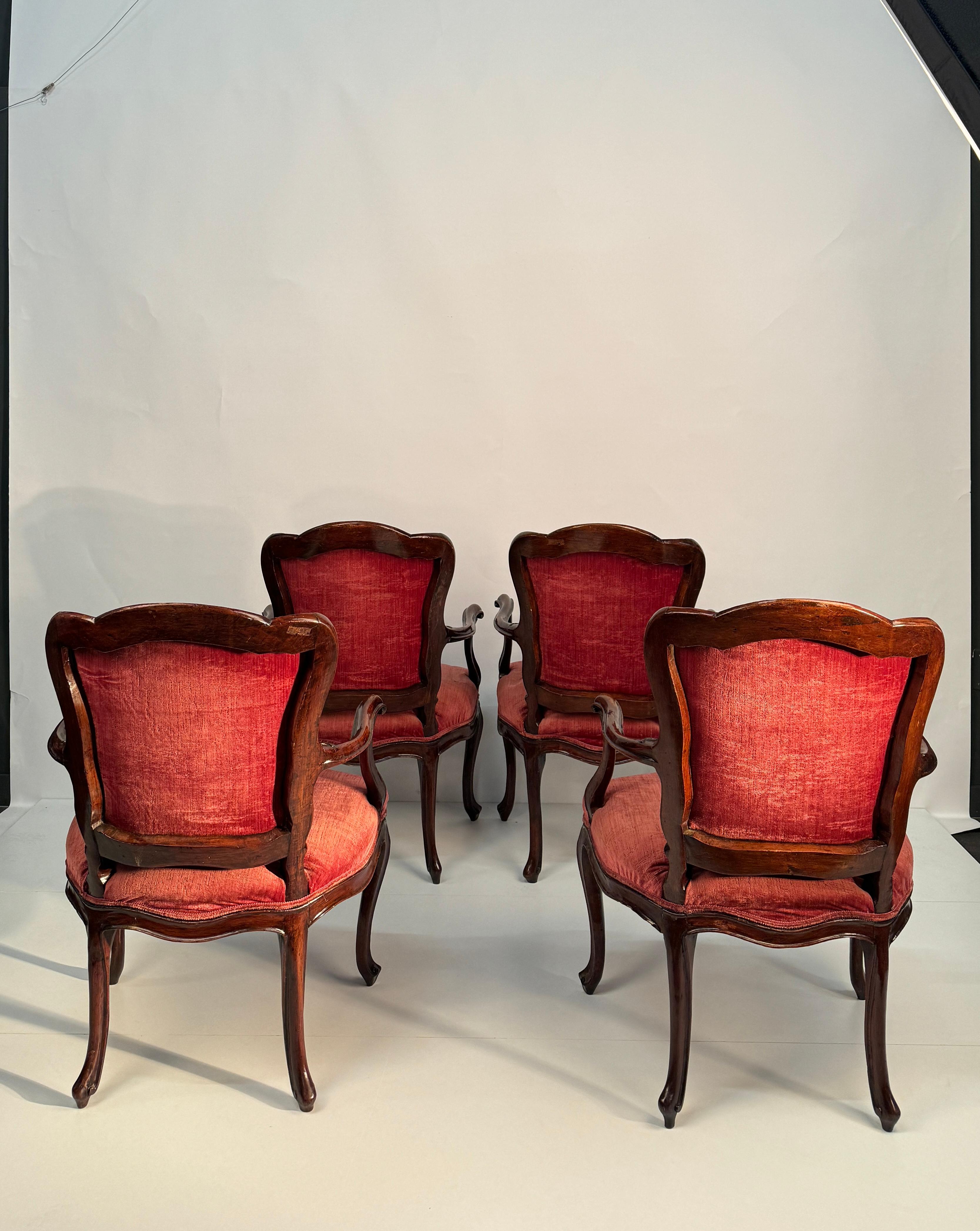 Quatre fauteuils en noyer, Venise, milieu du XVIIIe siècle, 
dossier légèrement galbé, accoudoirs et montants ondulés, ceinture décorée au centre d'une coquille sculptée, pieds cambrés, dossier et assise garnis de velours bleu 
cm 88x58x54