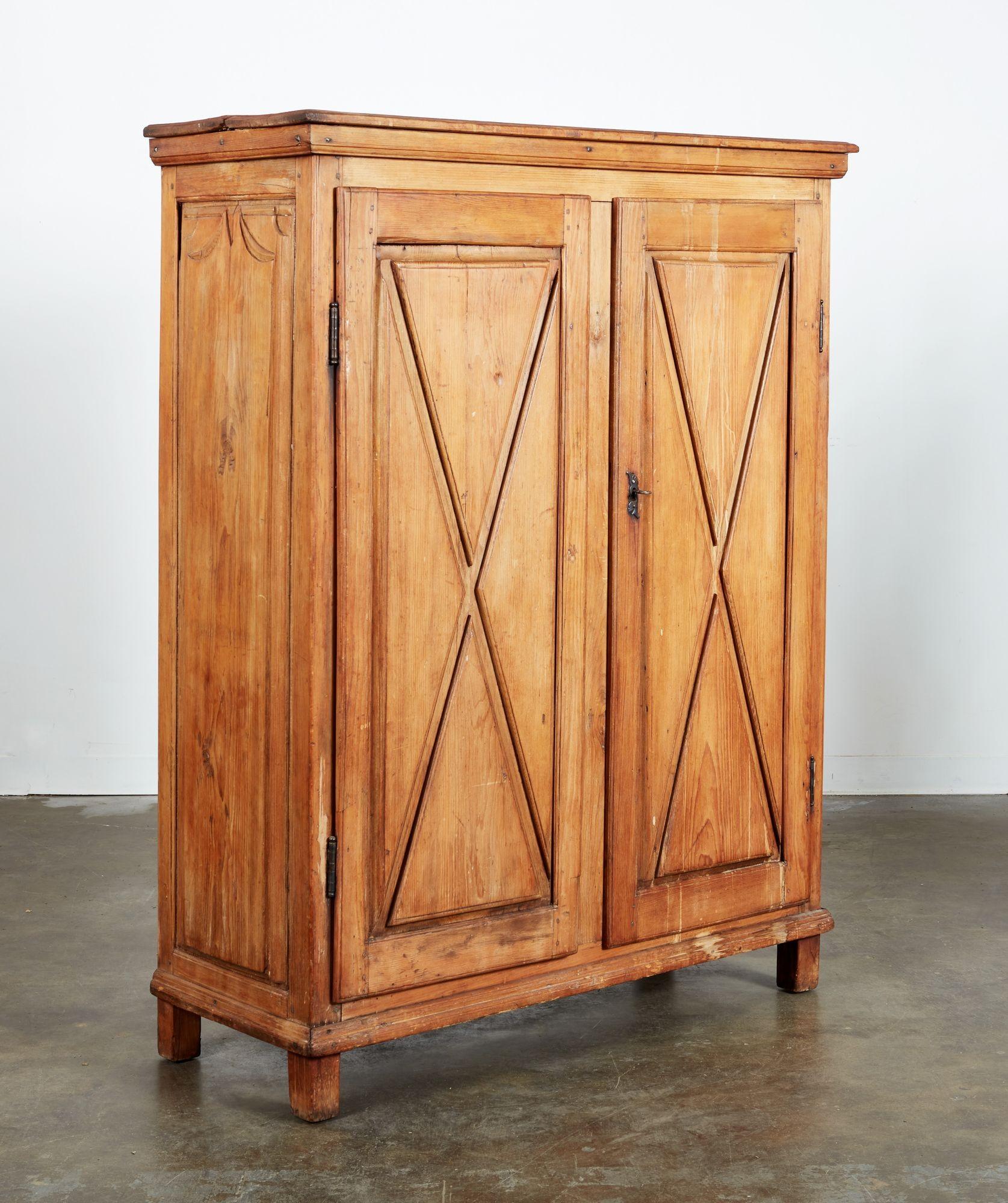 Armoire canadienne-française en pin à deux portes sur un étui étroit avec une corniche moulurée en surplomb, les portes comportant chacune des croix en X en feuillure dans un cadre rectangulaire, reposant sur des pieds à montants. L'intérieur est