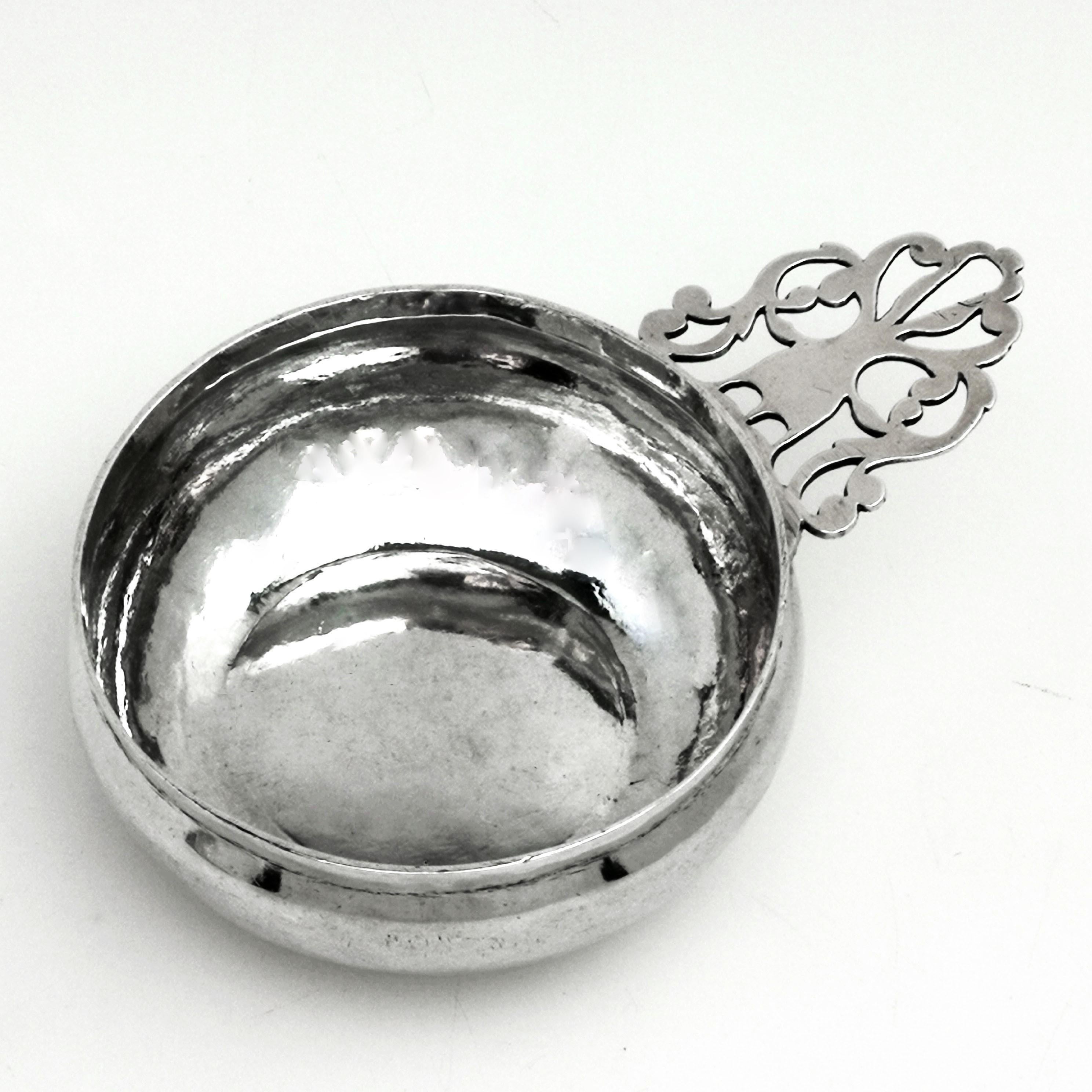 An excellent Queen Anne solid silver bleeding bowl / dish with a magnificent pierced handle. The bowl has a slightly bellied shape with a narrow straight sided upper rim. The underside of the handle is engraved with the letters T A T surrounding a