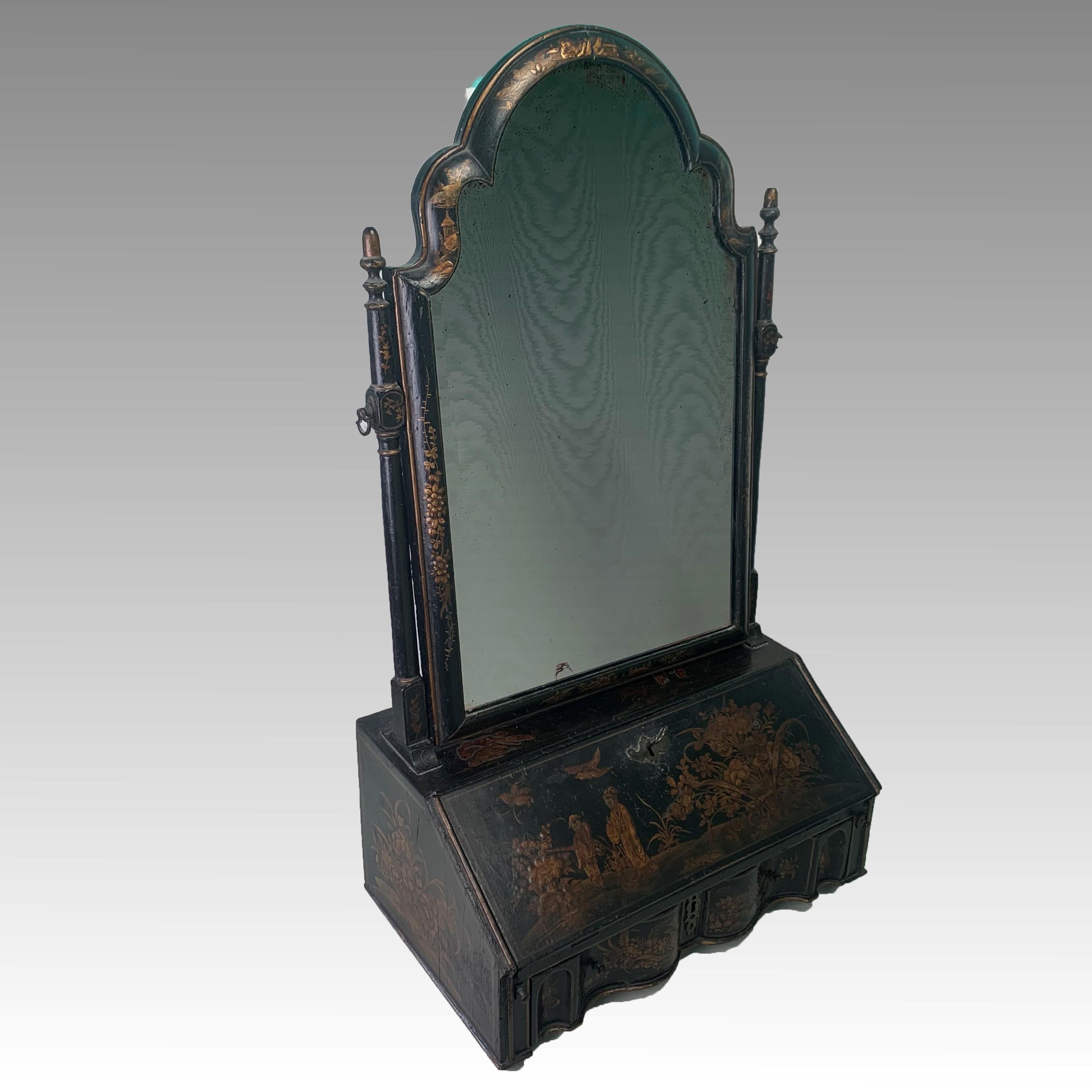 A fine and rare early 18th century Queen Anne period black Jappanned dressing table mirror witn shaped arched top above the original murcury plate with bevelled edge, supported on two turned uprights above a miniature bureau base. The fall opening