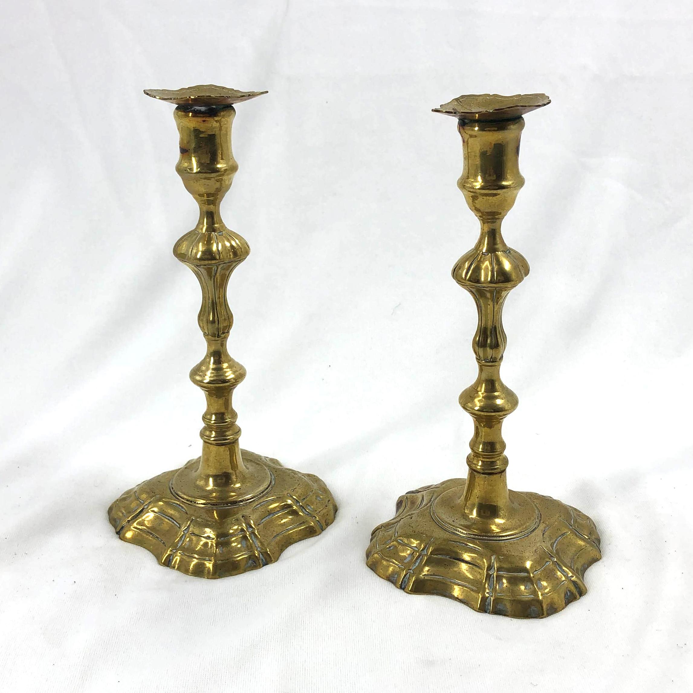 A pair of English Queen Anne turned brass candlesticks with stepped and lobed bases.