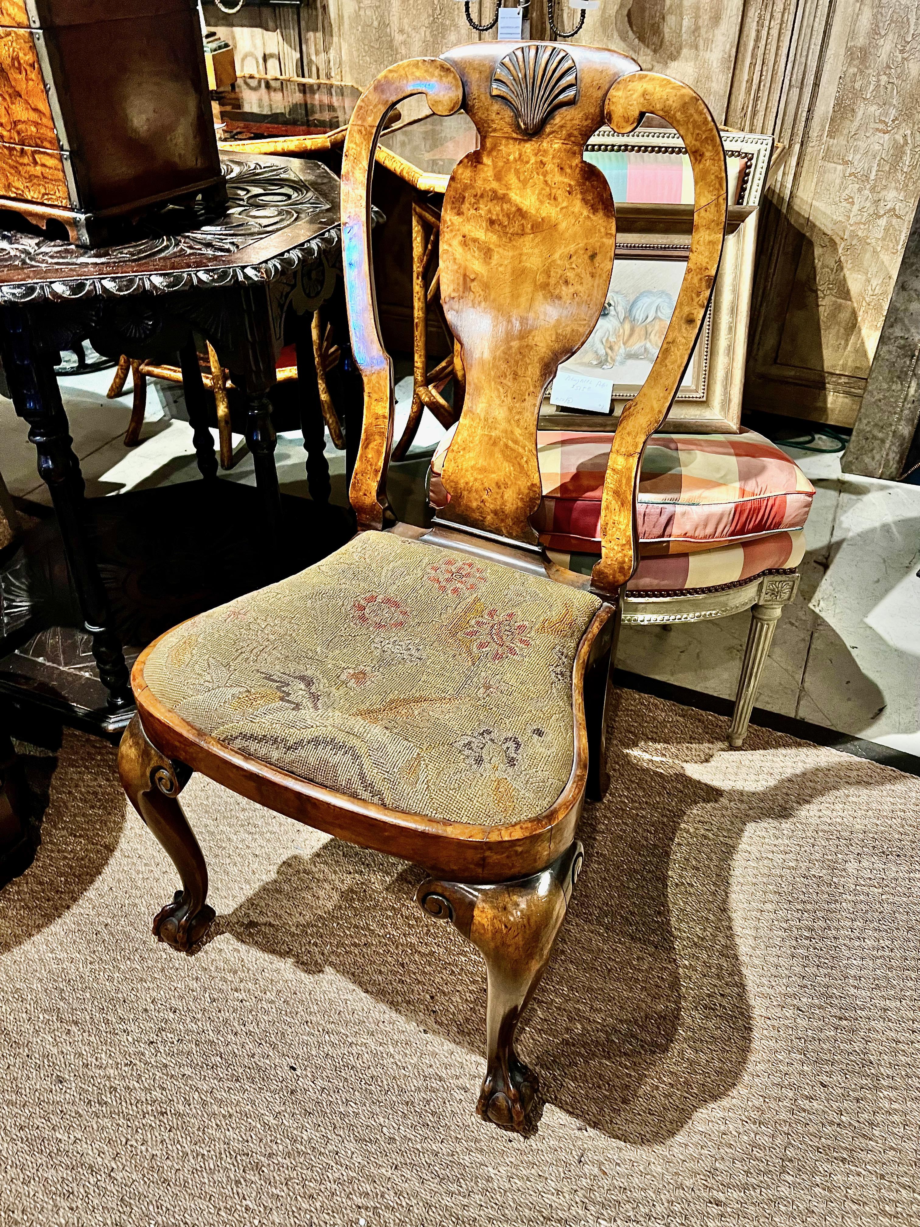 This is an extremely handsome Queen Anne Burl Walnut side chair. The chair features a finely carved shell to the crest rail, beautiful burl walnut veneer, carved knees and claw and ball feet. The compass seat has retained its 18th century needlework