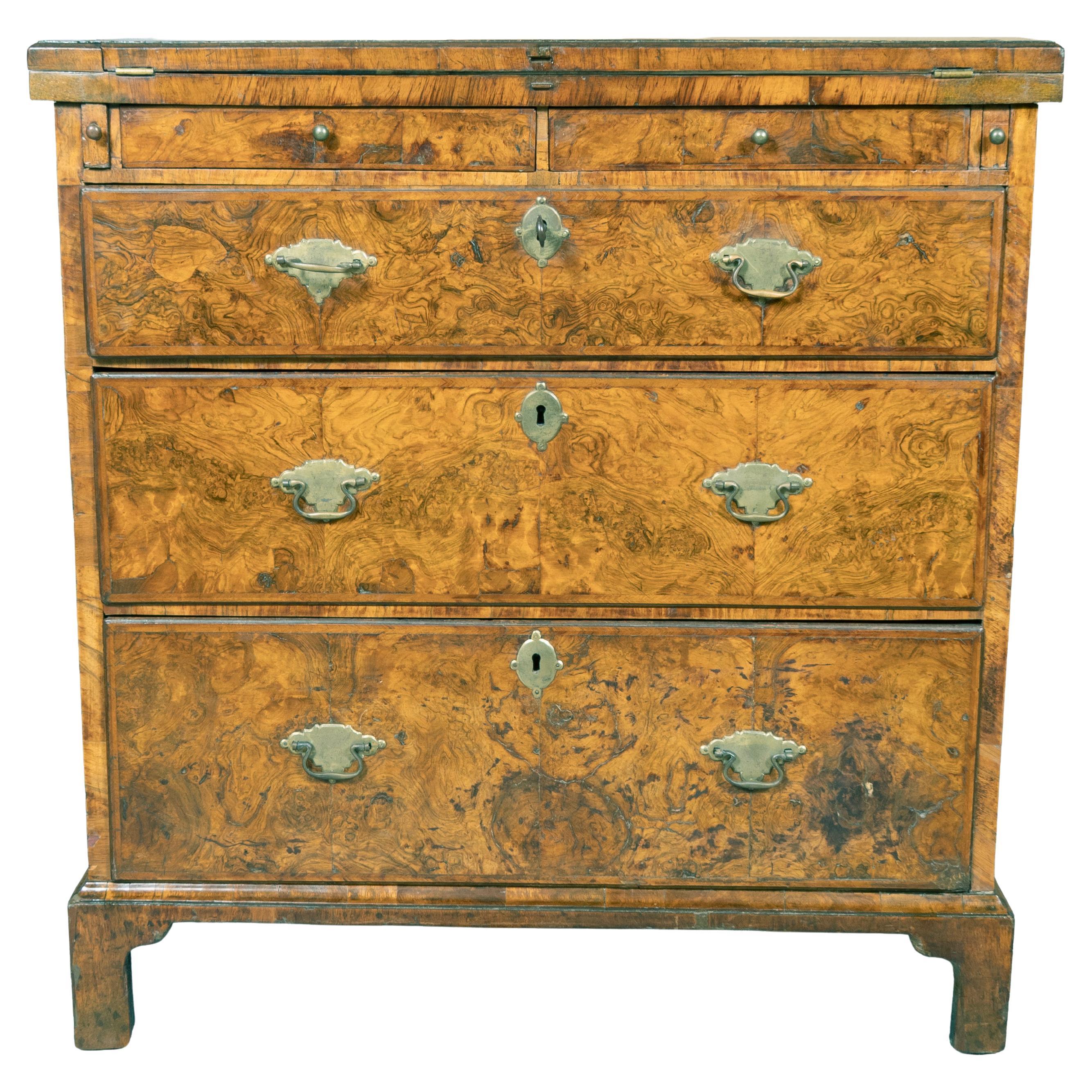 With rectangular quarter veneered hinged top that flips forward to form a writing surface over two small valuables drawers and three graduated drawers. Bracket feet. Original handles with keys. A fine classic and often sought after rare form. By