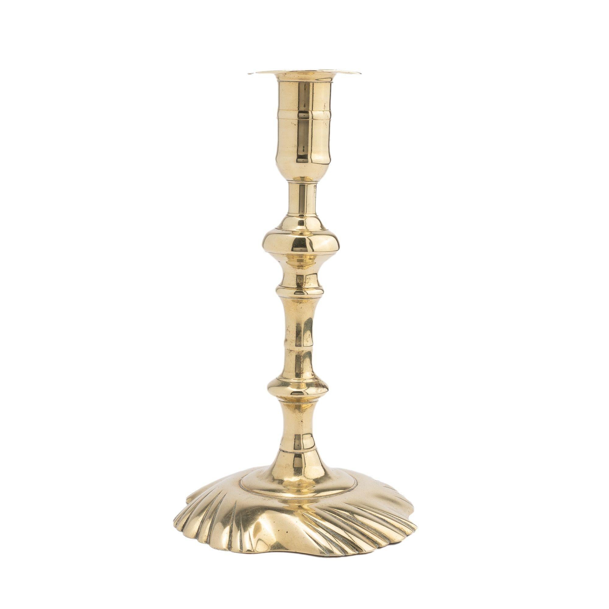 Hollow core cast brass candlestick with swirl base peened to a knobbed candle shat supporting a candle cup with bobeche.

Birmingham, England, 1750-75.