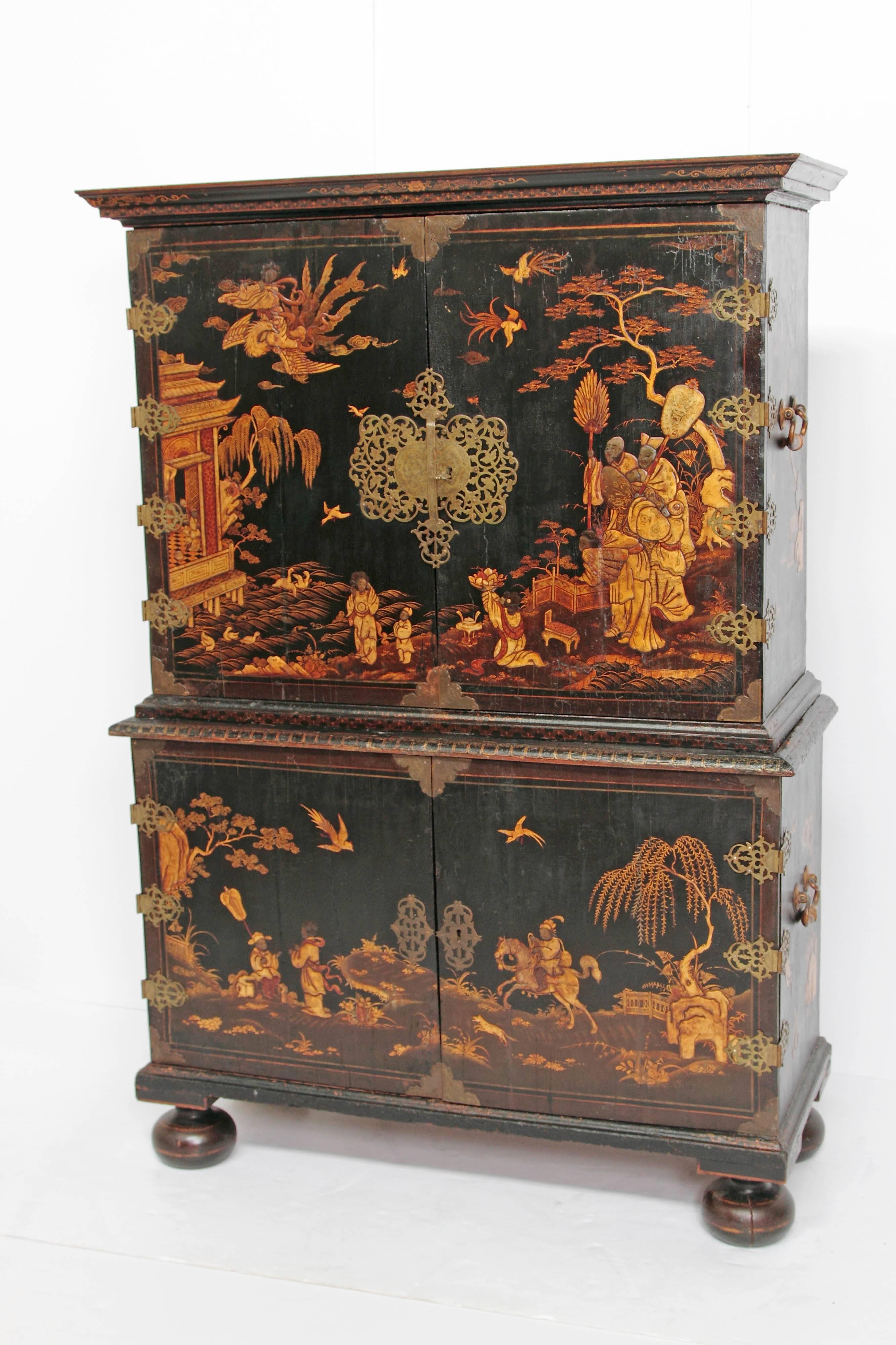 An English Queen Anne period collectors cabinet, black lacquer with raised gold decoration / Japanned (with chinoiserie decoration), two doors at top open to expose six (6) drawers, beside two (2) shelves, and a compartment with a door, base has two