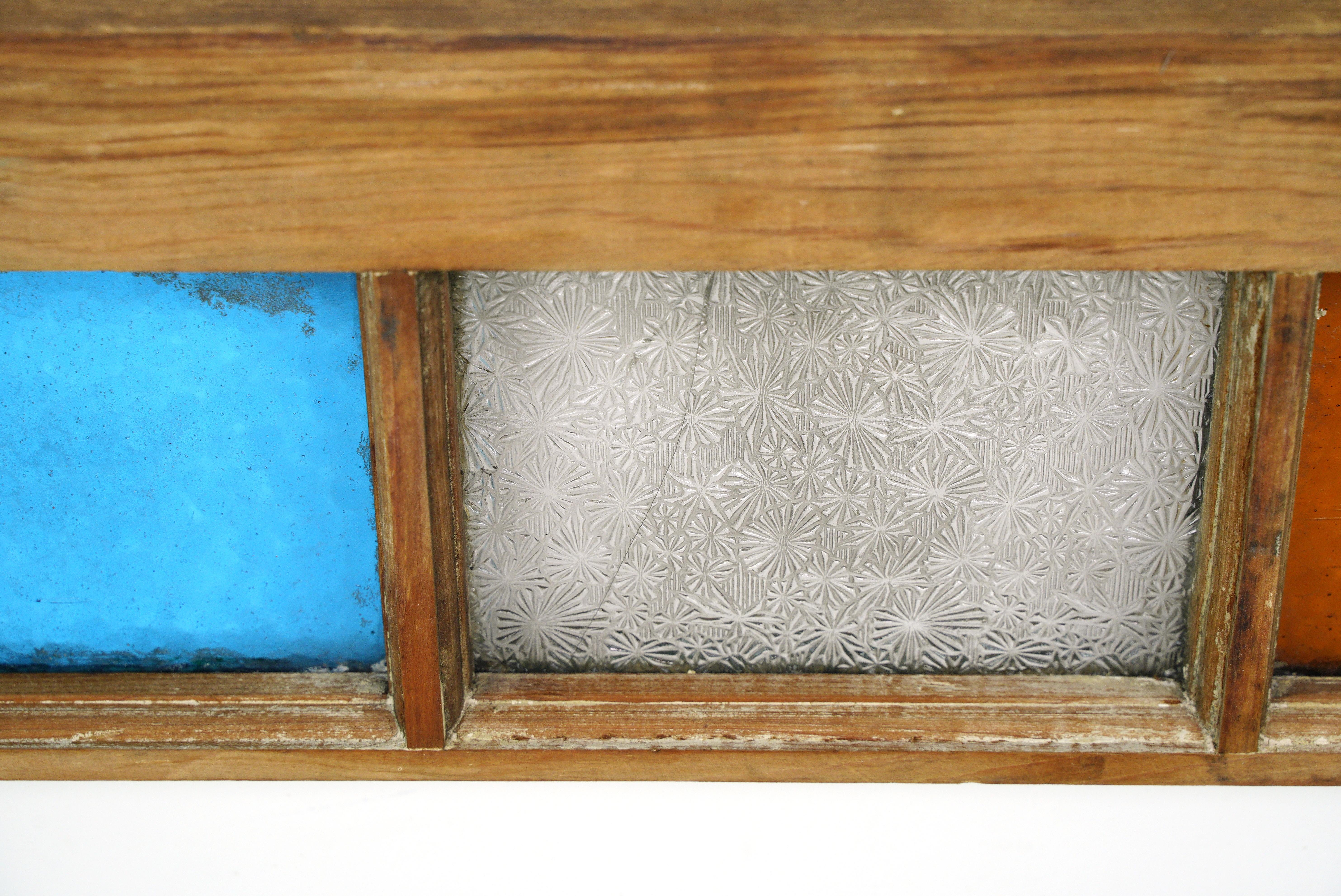 This antique stained glass window is a stunning and historical architectural element. Crafted with a pine frame, it features vibrant stained glass in a Queen Anne style design. Stained glass windows like these were often used in homes and buildings