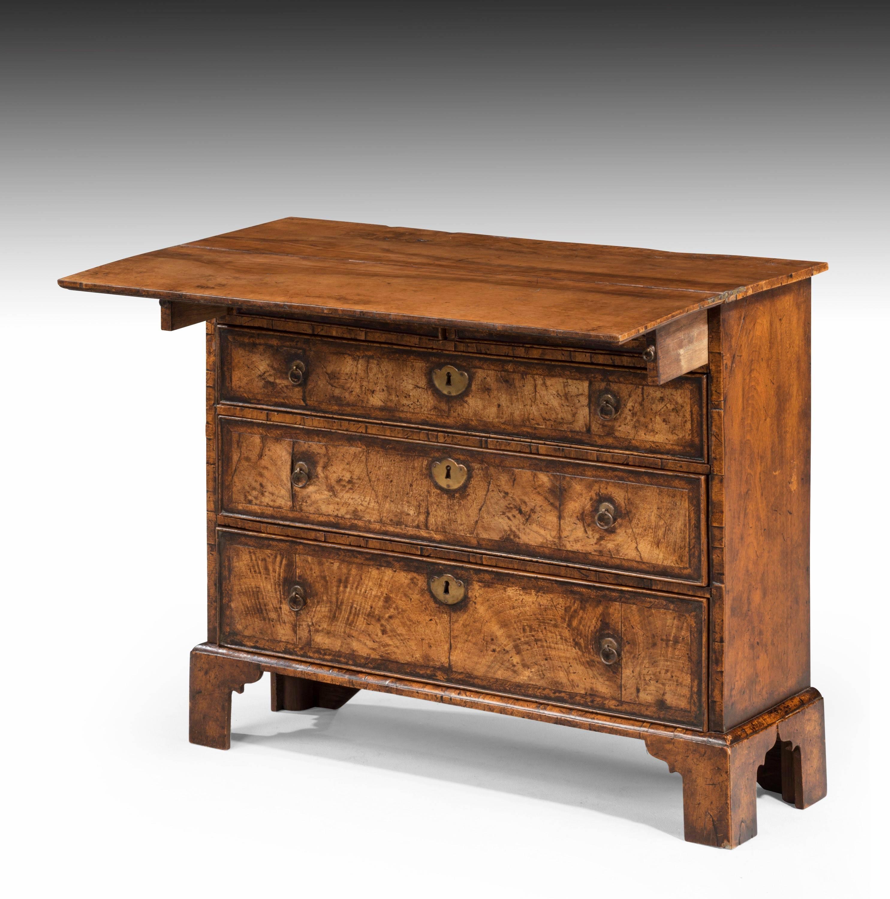 A beautifully figured and constructed walnut bachelor’s chest of Queen Anne design. Evenly faded color to the dark rich honey. The fold over top and the overall carcass of unusually slender proportions. Should be circa 1705-1710 but in fact a fake