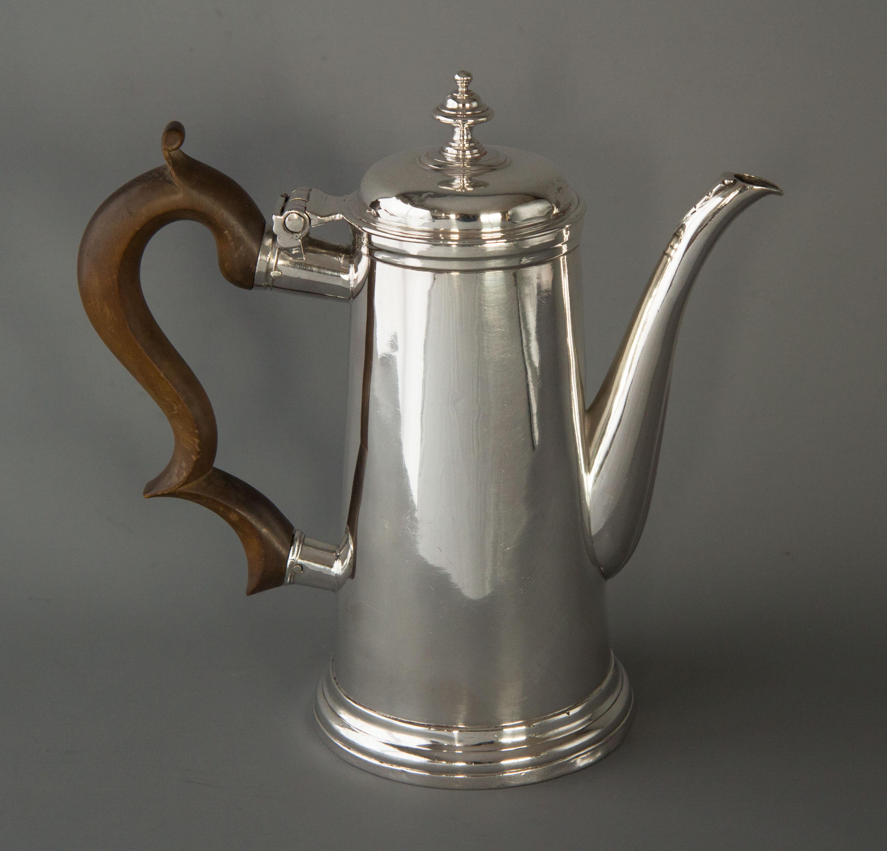 A very rare and excellent quality Irish Queen Anne silver coffee pot of plain tapering cylindrical form, leaf-capped spout, low domed well fitting lid with cast finial. Original scroll fruit wood handle. The whole standing on a stepped circular