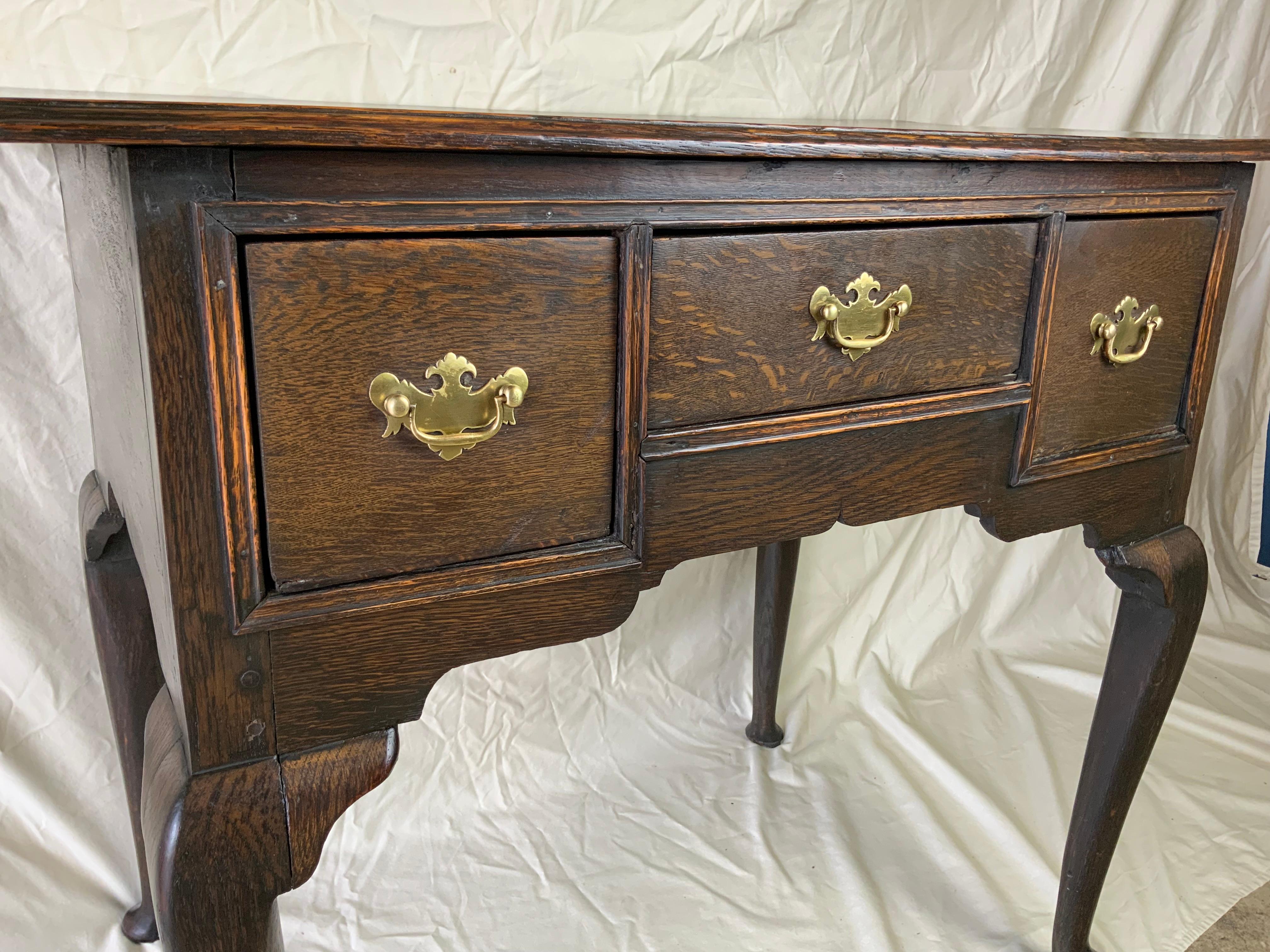 A very nice Queen Anne Oak lowboy with a large overhanging molded edge top over three drawers.  Original hardware, locks and finish on this early lowboy. Molded beaded moldings on the case surround the drawer faces. Great old color and patina. 