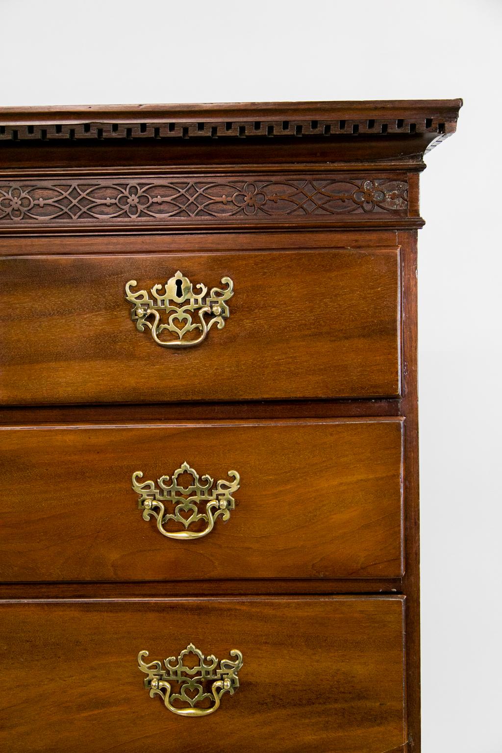 The top section of this Queen Anne highboy has a crown with Wall of Troy molding and a blind fretwork frieze carved in the manner of Thomas Elfe of 18th century Charleston, SC. The drawers have a lipped edge. The legs have a carved shell on the knee