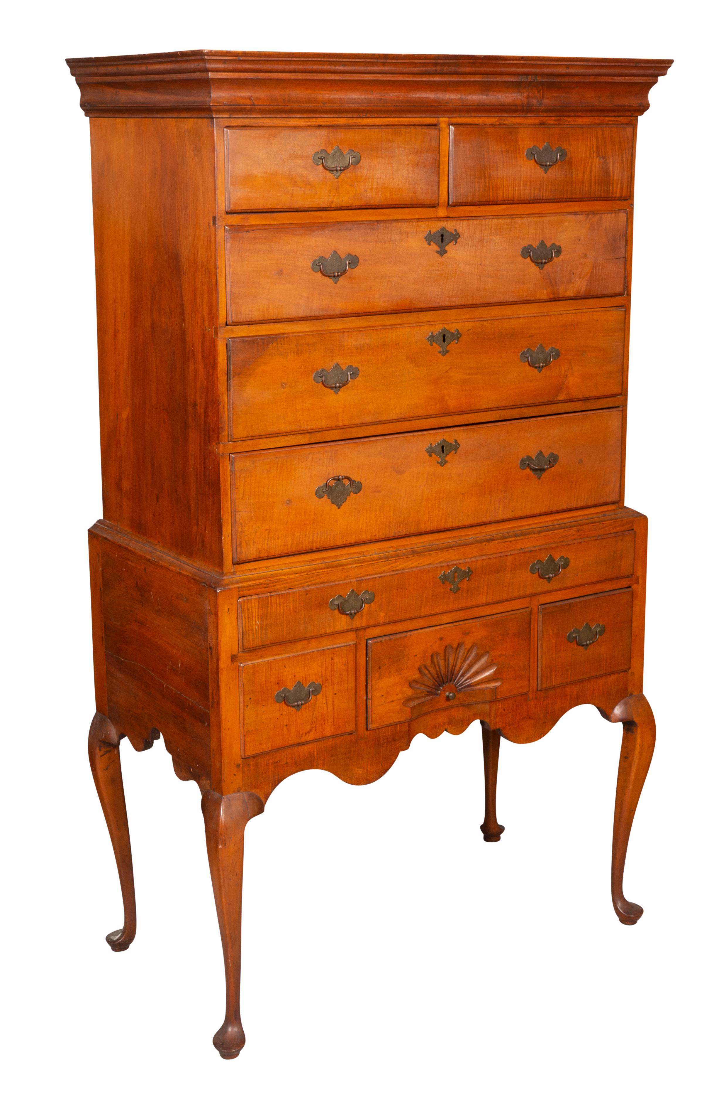 Rectangular cornice over two over three drawers, base with a long drawer over two drawers flanking a fan carved drawer, raised on cabriole legs and pad feet.