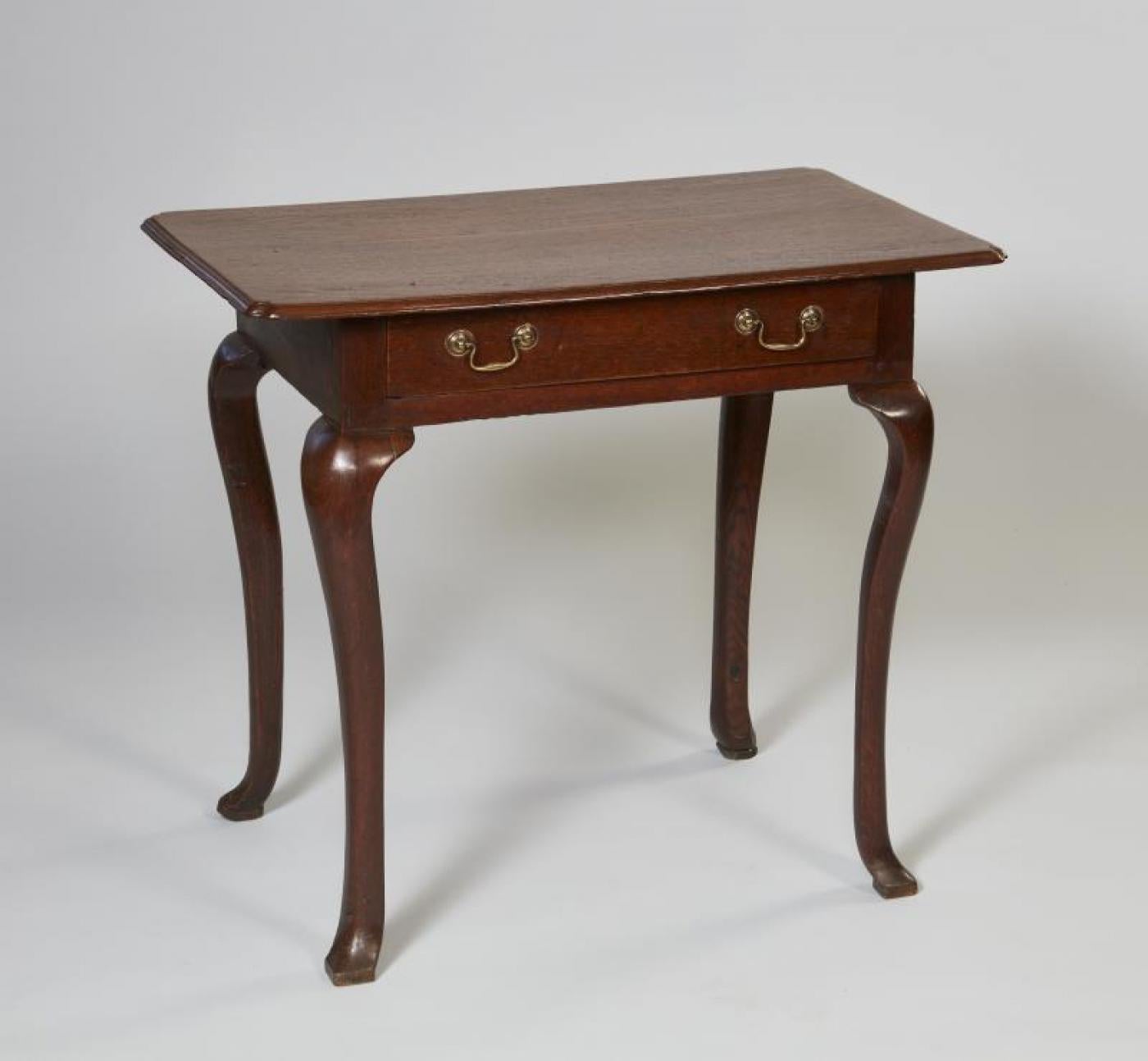 Early 18th century English oak padfoot side table, the quarter sawn oak top with molded edge and re-entrant corners over single drawer, the shaped cabriole legs ending in square pad feet, the whole with good mellow color and patina.